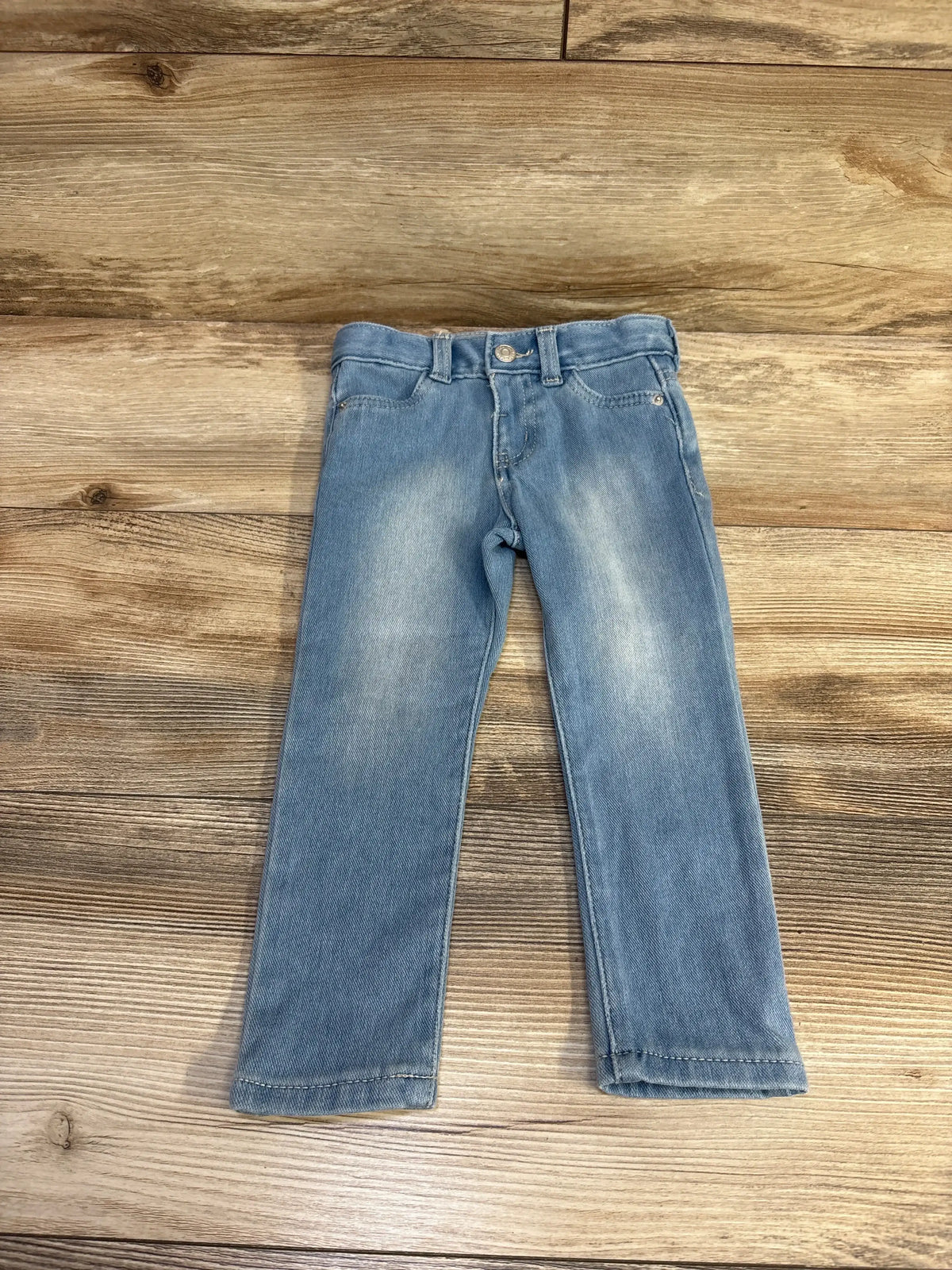Front view of Cat & Jack blue jeggings in size 2T showcasing adjustable waist and front pockets on wood plank background