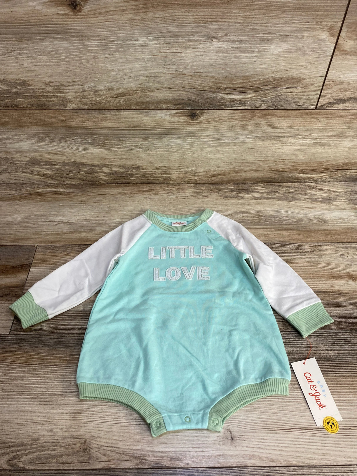 Mint green Cat & Jack baby romper with 'Little Love' text, laid on wooden floor
