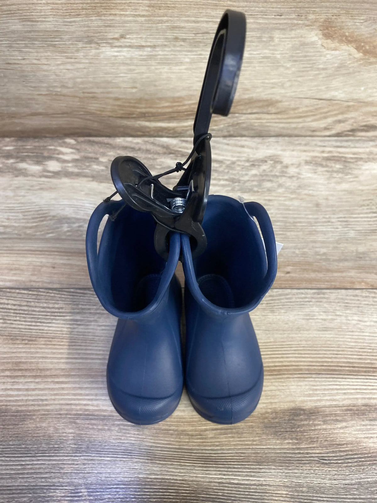 Top-down view of BEARPAW EVA toddler navy rain boots showing easy pull-on handles on wood floor background