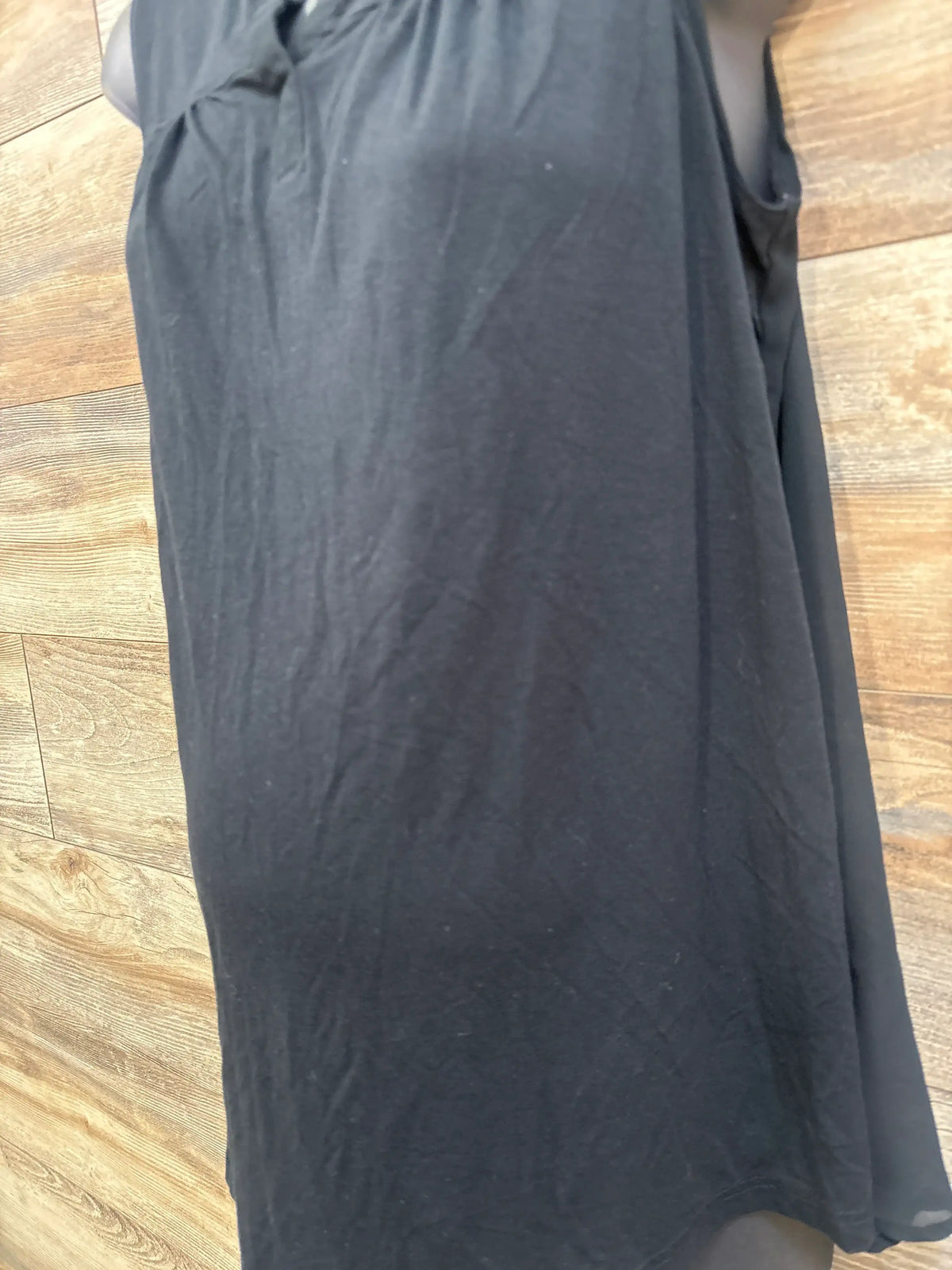 Back view of Liz Lange black sheer back tank top in size XS showcasing its sheer back panel on a wood floor
