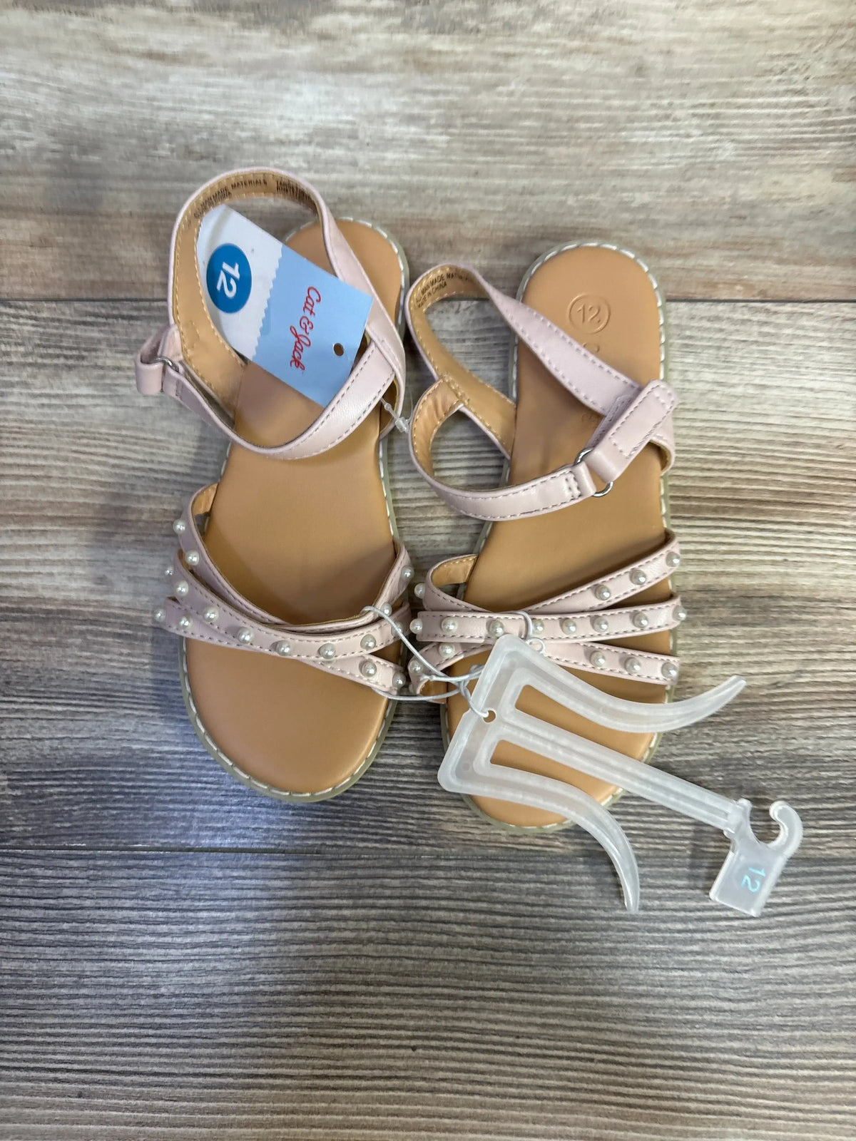 Top-down view of Cat & Jack Jen toddler pearl-strap sandals in blush showcasing pearl embellishments, adjustable ankle straps, and visible size 12C tag on wood background