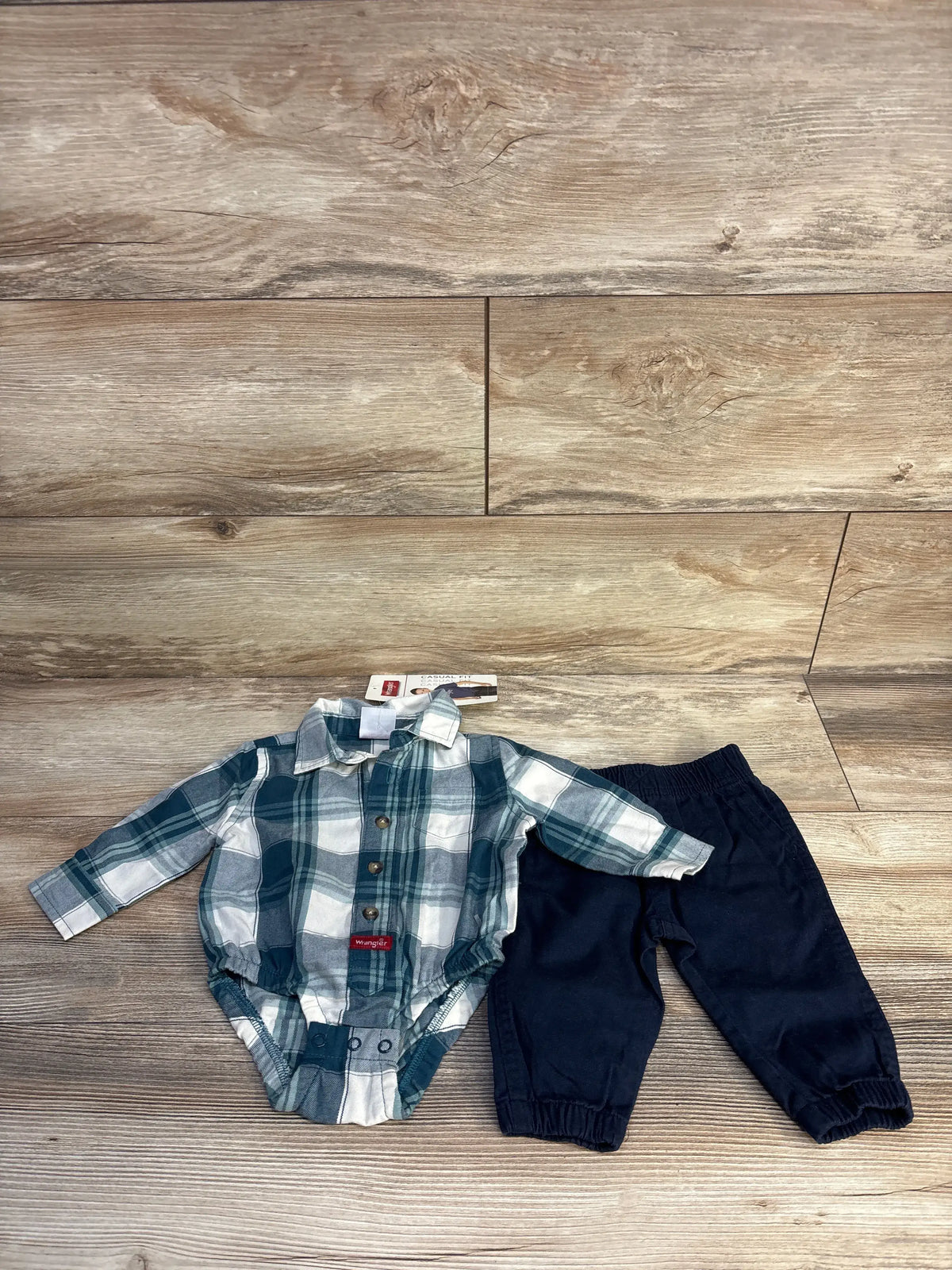 Front view of Wrangler two-piece plaid bubble romper and pants set showcasing button-up front on a wood floor