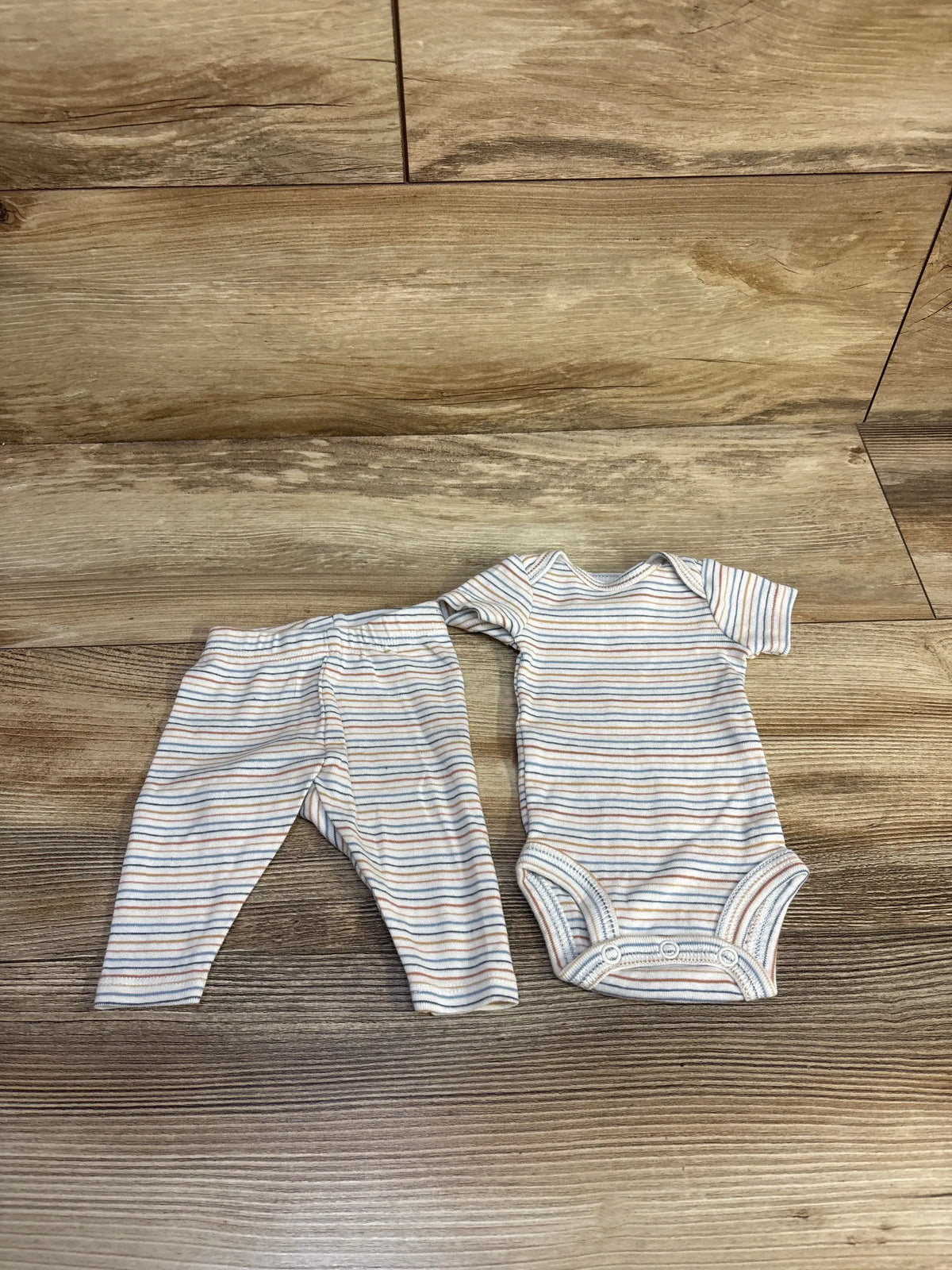 Front view of Just One You white 2-piece striped bodysuit and bottoms set showing snap closures on a wood floor