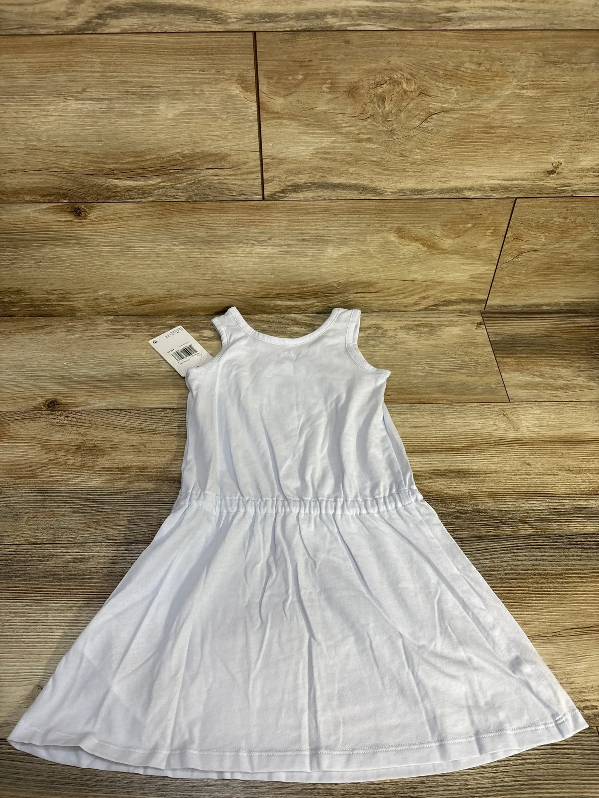 Flat lay of Nike girls’ light blue tank dress showing sleeveless bodice and gathered elastic waist, size 5T on wood floor