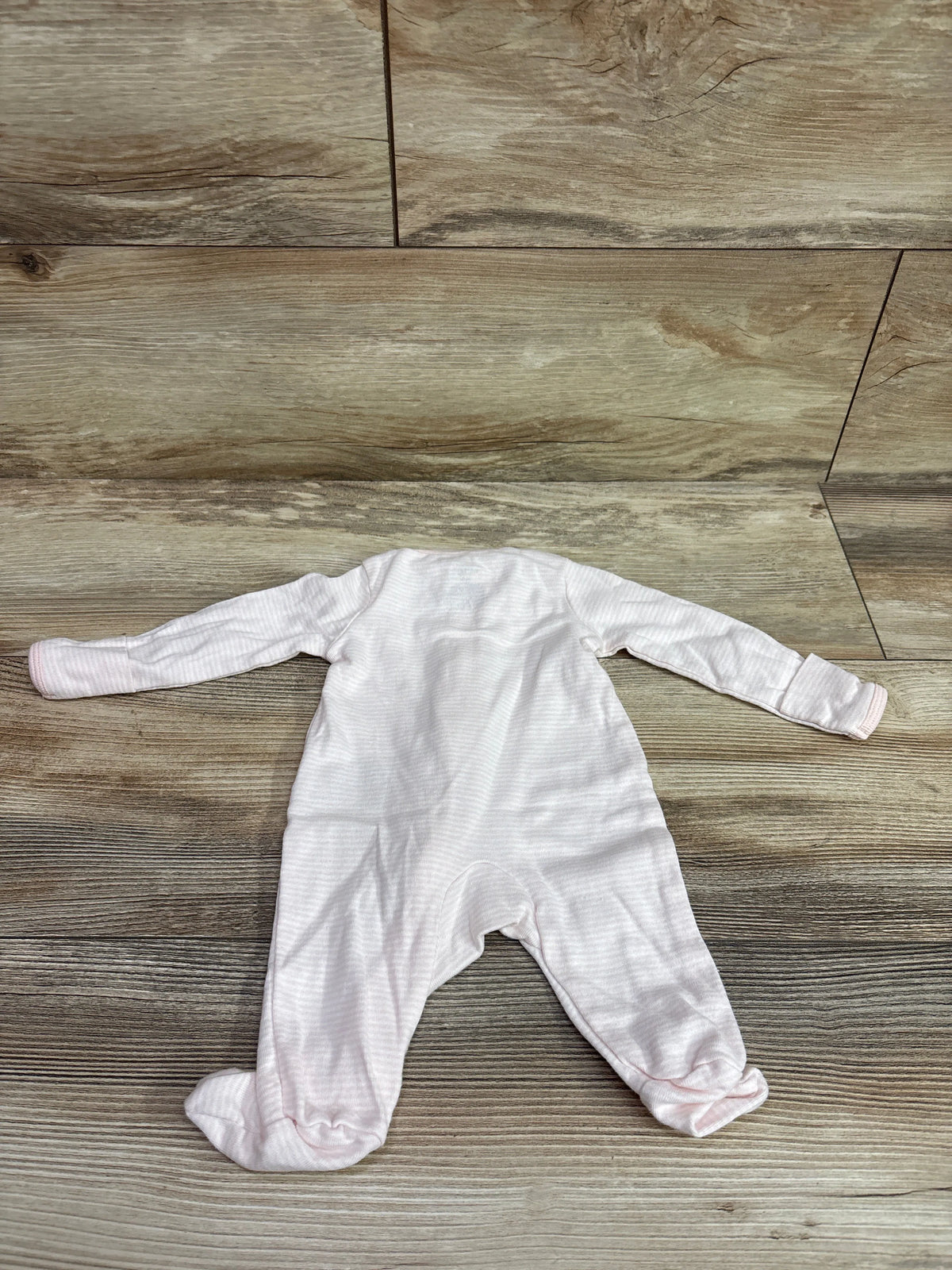 Front view of Carter’s striped pink sleeper in newborn size showcasing long sleeves and covered feet on a wood background