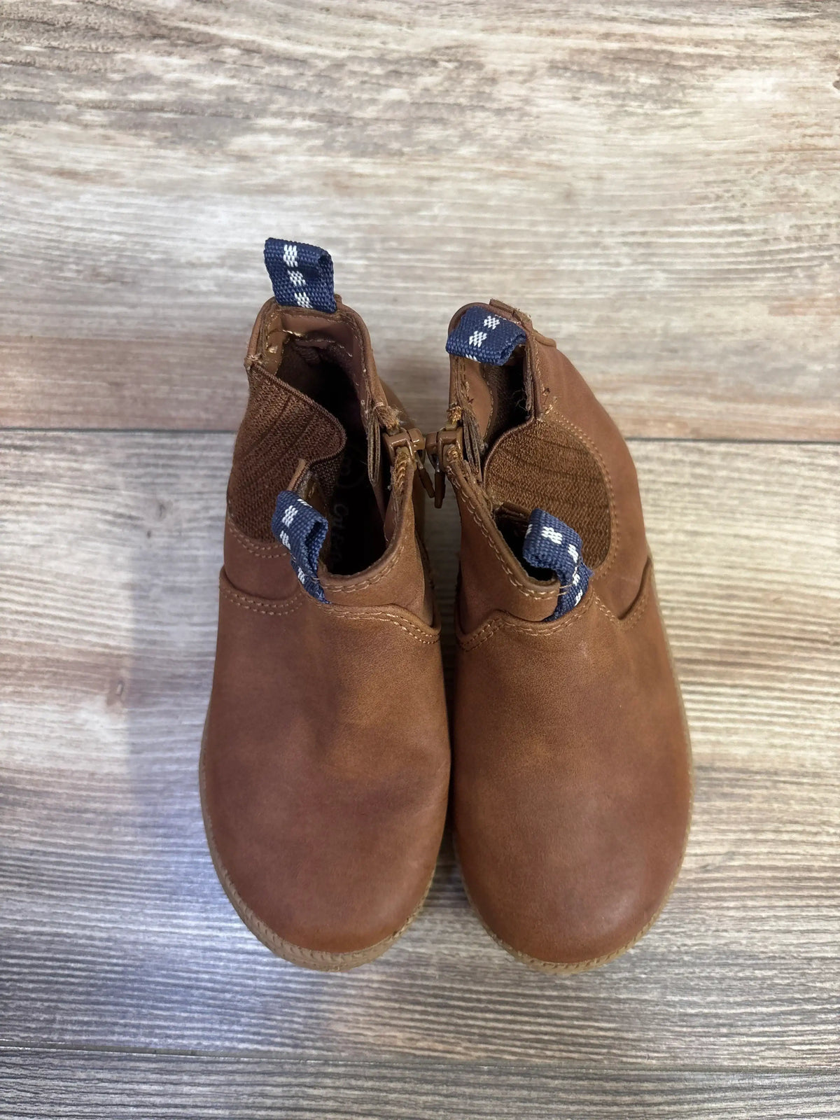 Top view of Cat & Jack toddler brown zipper boots showing side zippers, elastic ankle panels and navy pull tabs on wood floor