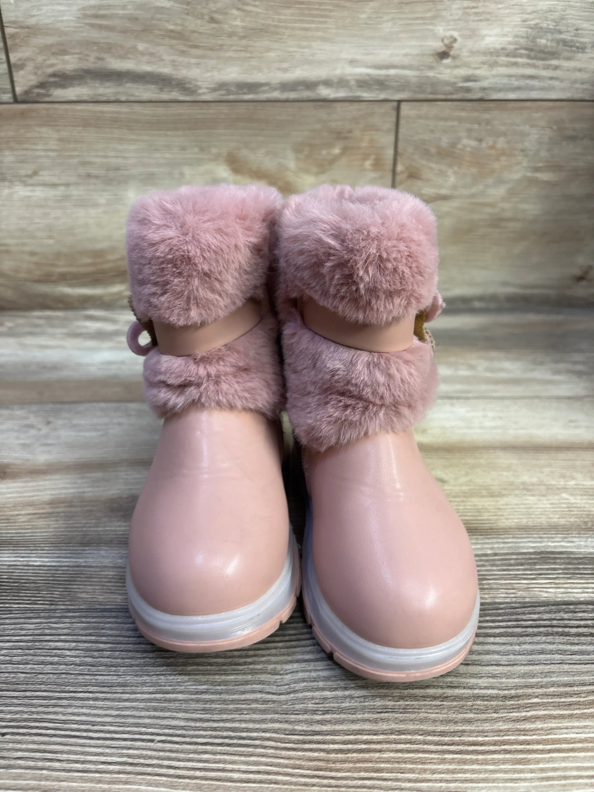 Front view of Belladia pink faux fur boots in size 6C showcasing plush fur cuffs with a wood plank background