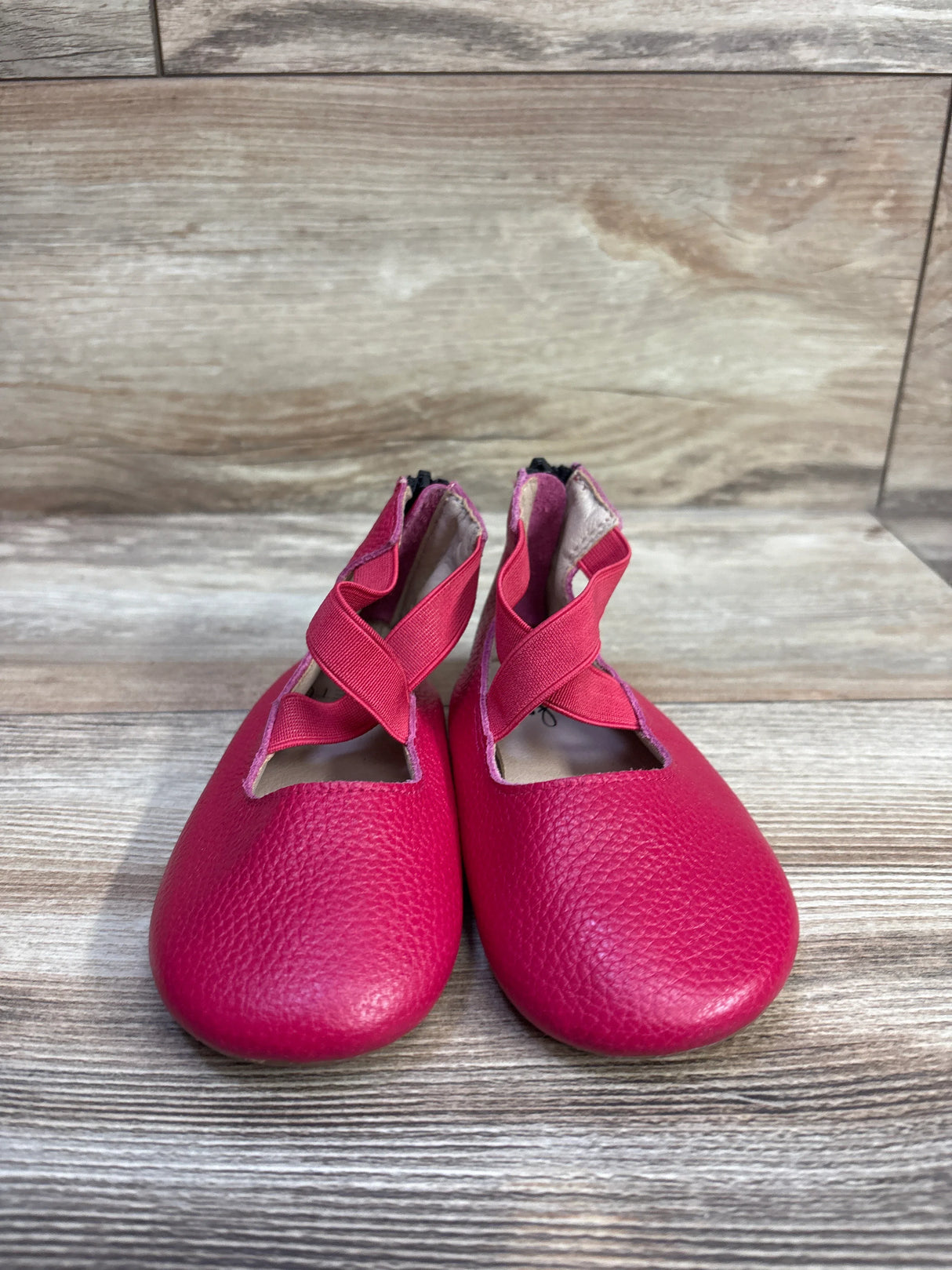 Front view of Monkey Feet Mary Jane ballet flats in pink with criss-cross elastic straps on wood background