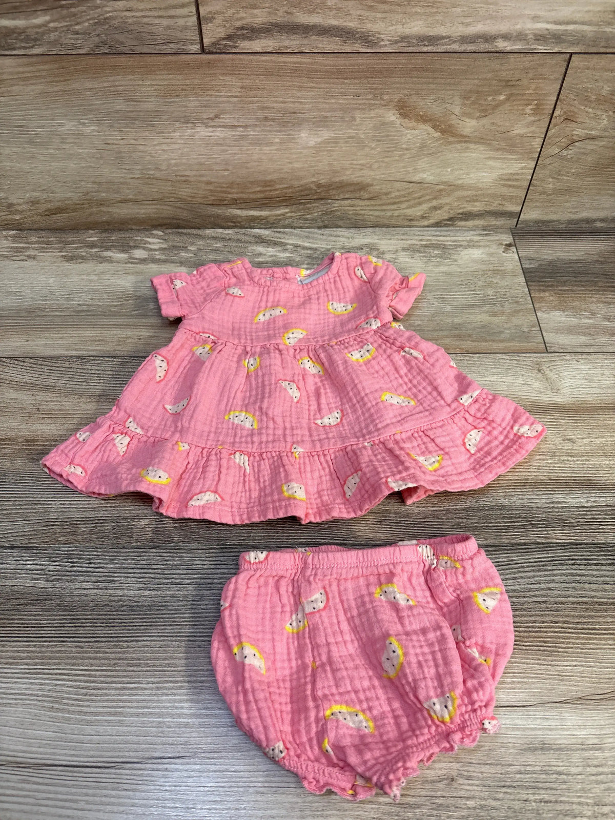 Flat lay of pink Koala Baby gauze dress and matching bloomers (3M) showing ruffle hem and elasticized bloomers on wooden floor
