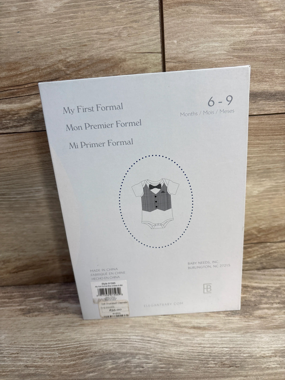 Back of Elegant Baby My First Formal onesie box showing tuxedo print and size 6-9 months on wood background