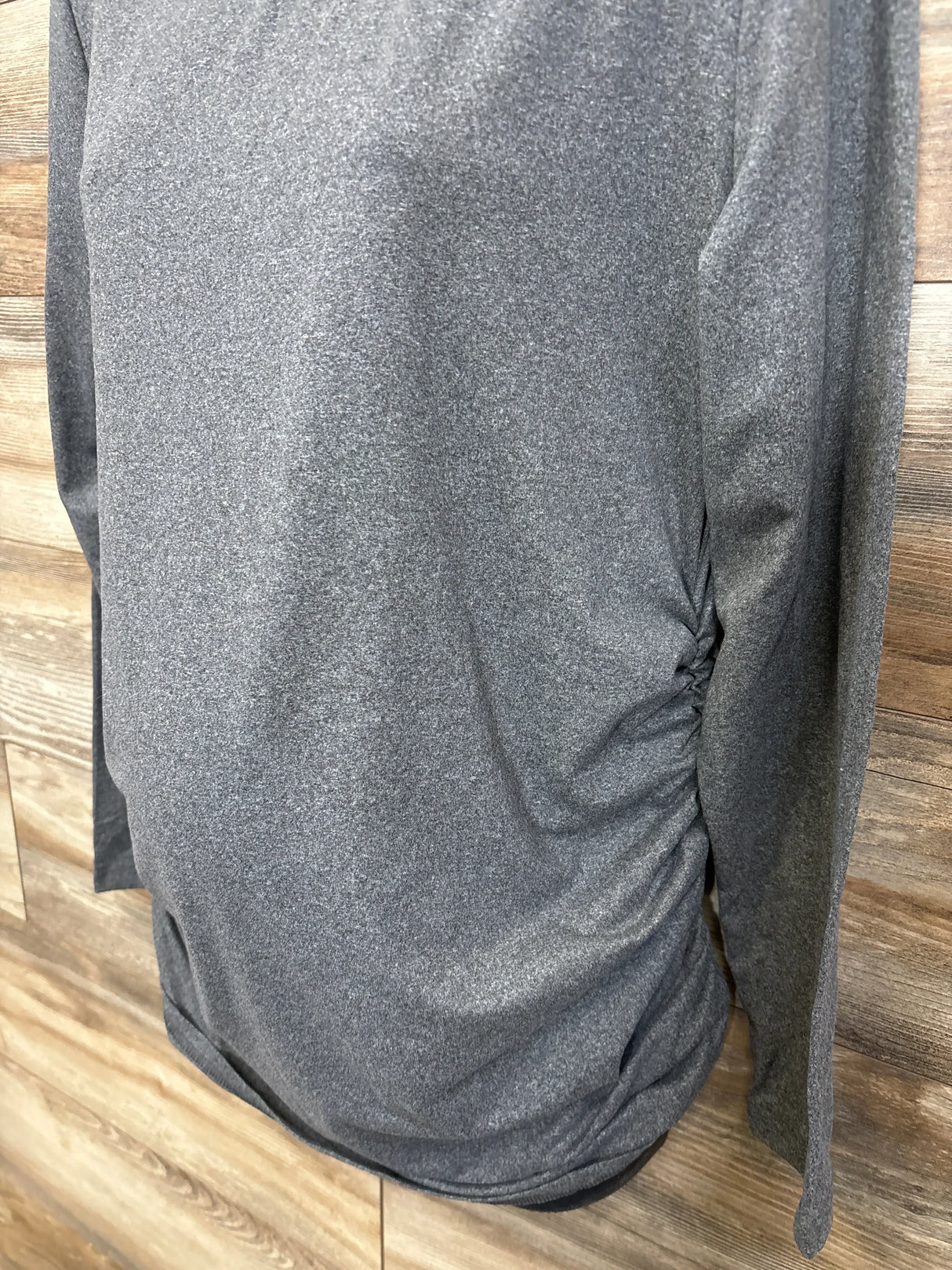 Gray long sleeve maternity top with side ruching, displayed on a wooden background