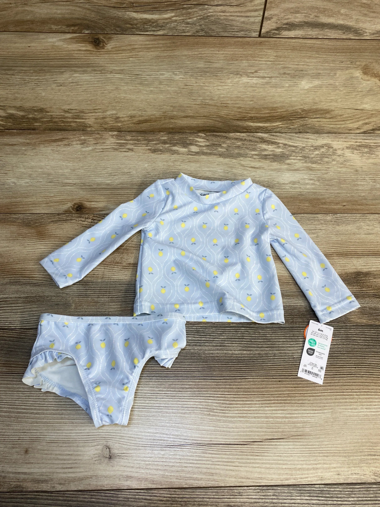Baby long sleeve rash guard swimsuit set with yellow lemon print, size 6m, on wood background