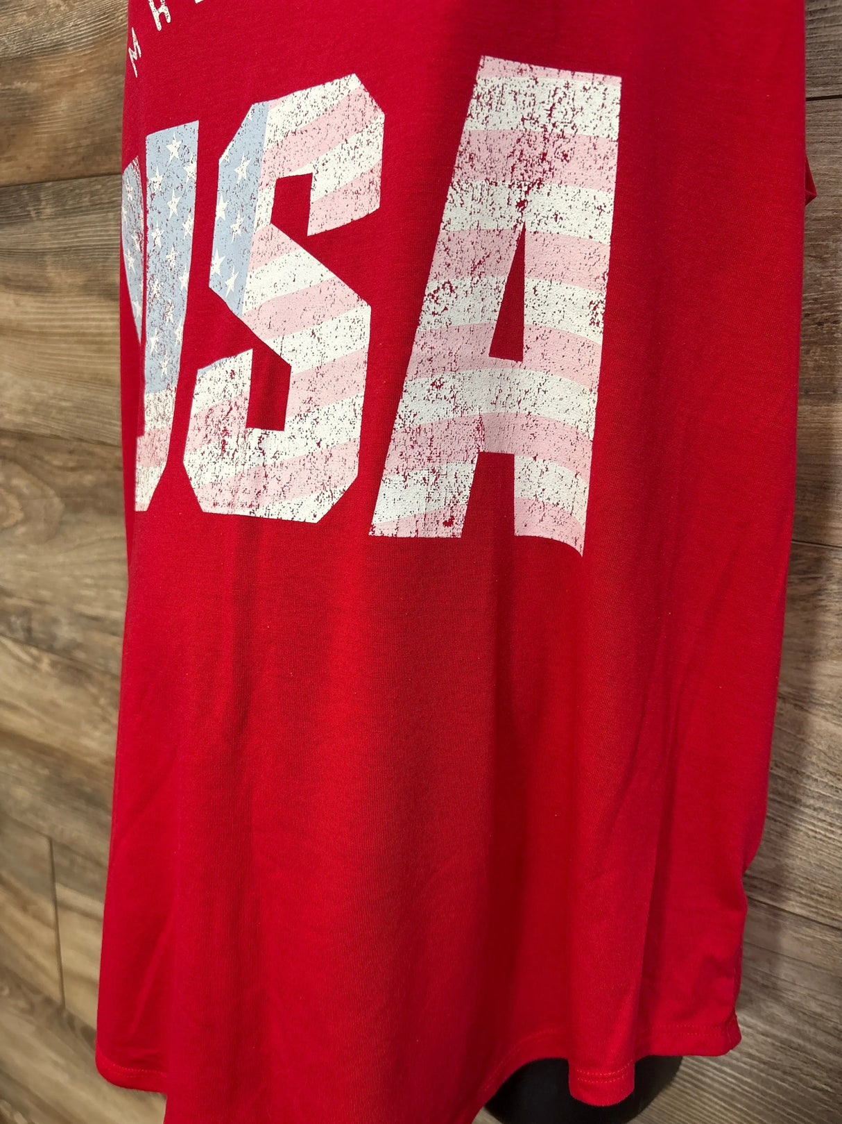 Close-up front of red Isabel Maternity tank top showing large distressed USA flag print with wood plank background