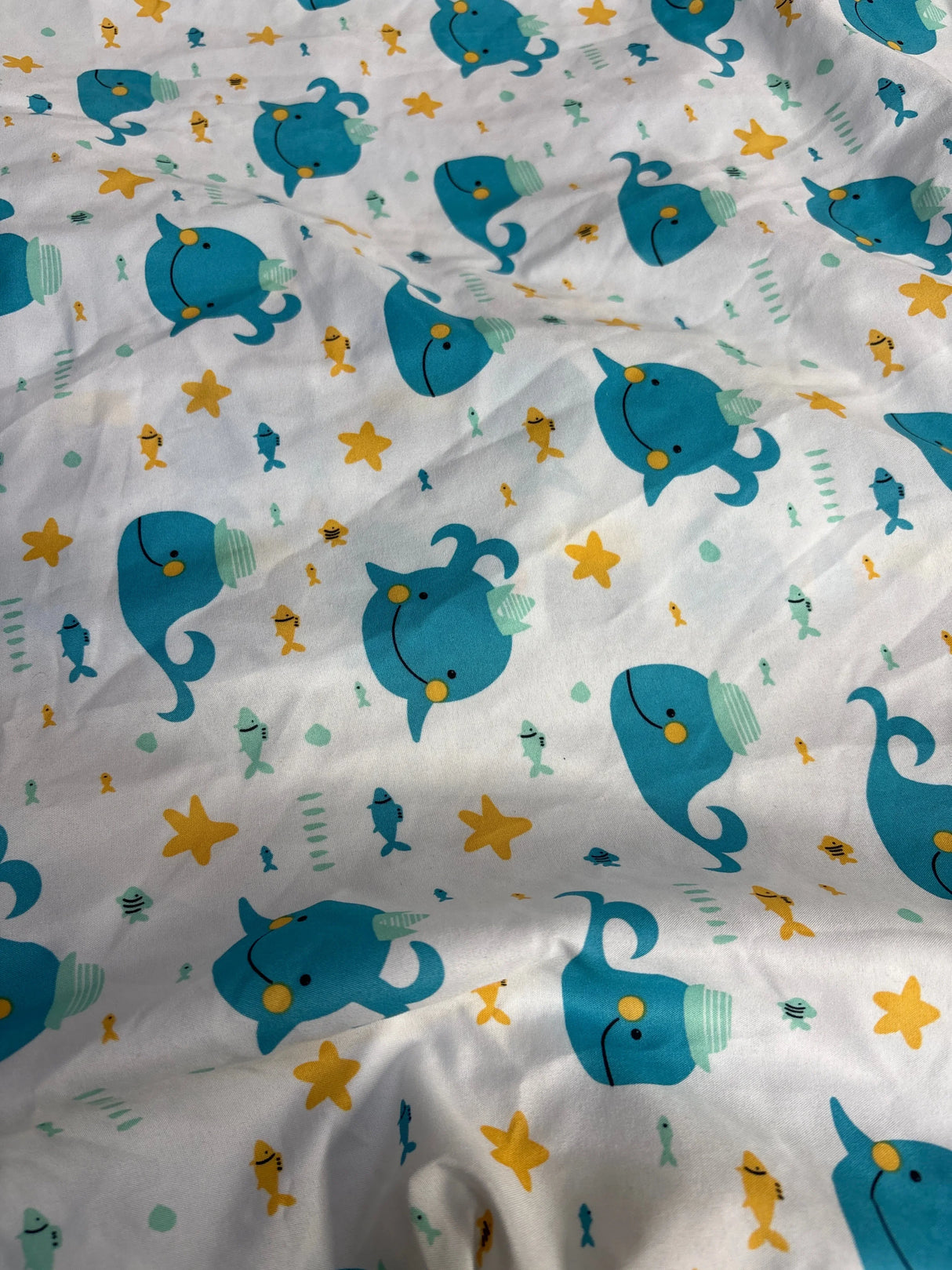 White fabric with cute blue whales, yellow starfish, and colorful small fish pattern