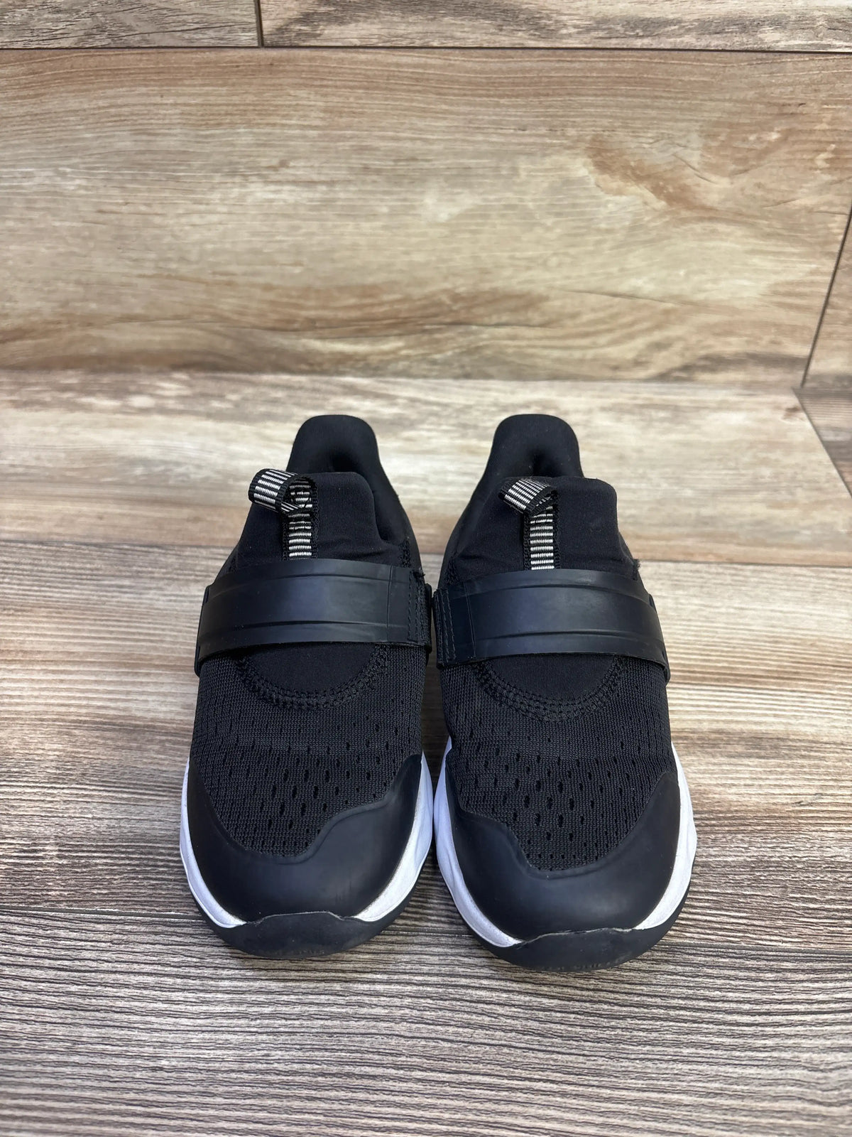 Front view of black All In Motion Dannie slip-on performance sneakers with knit uppers and white soles on wood flooring