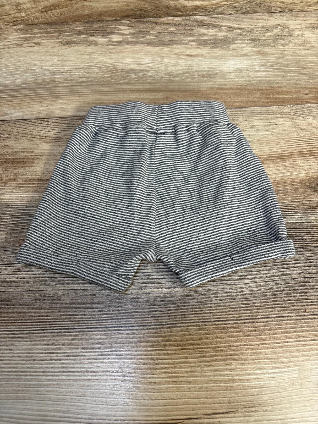 Gray and white striped baby shorts with elastic waistband on wood background