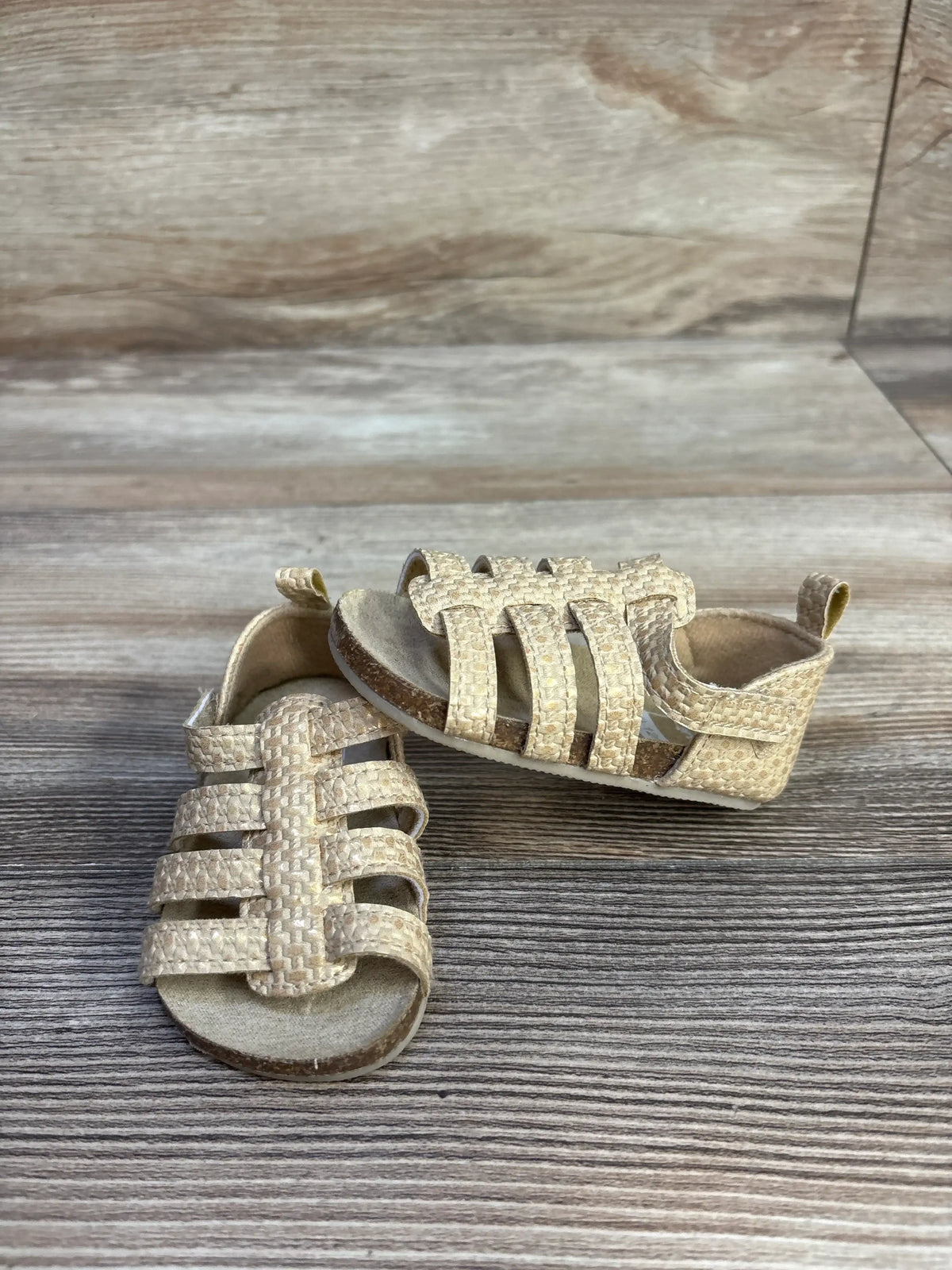 Top view of Carter’s strappy sandals showcasing multiple secure straps on a wood-look background
