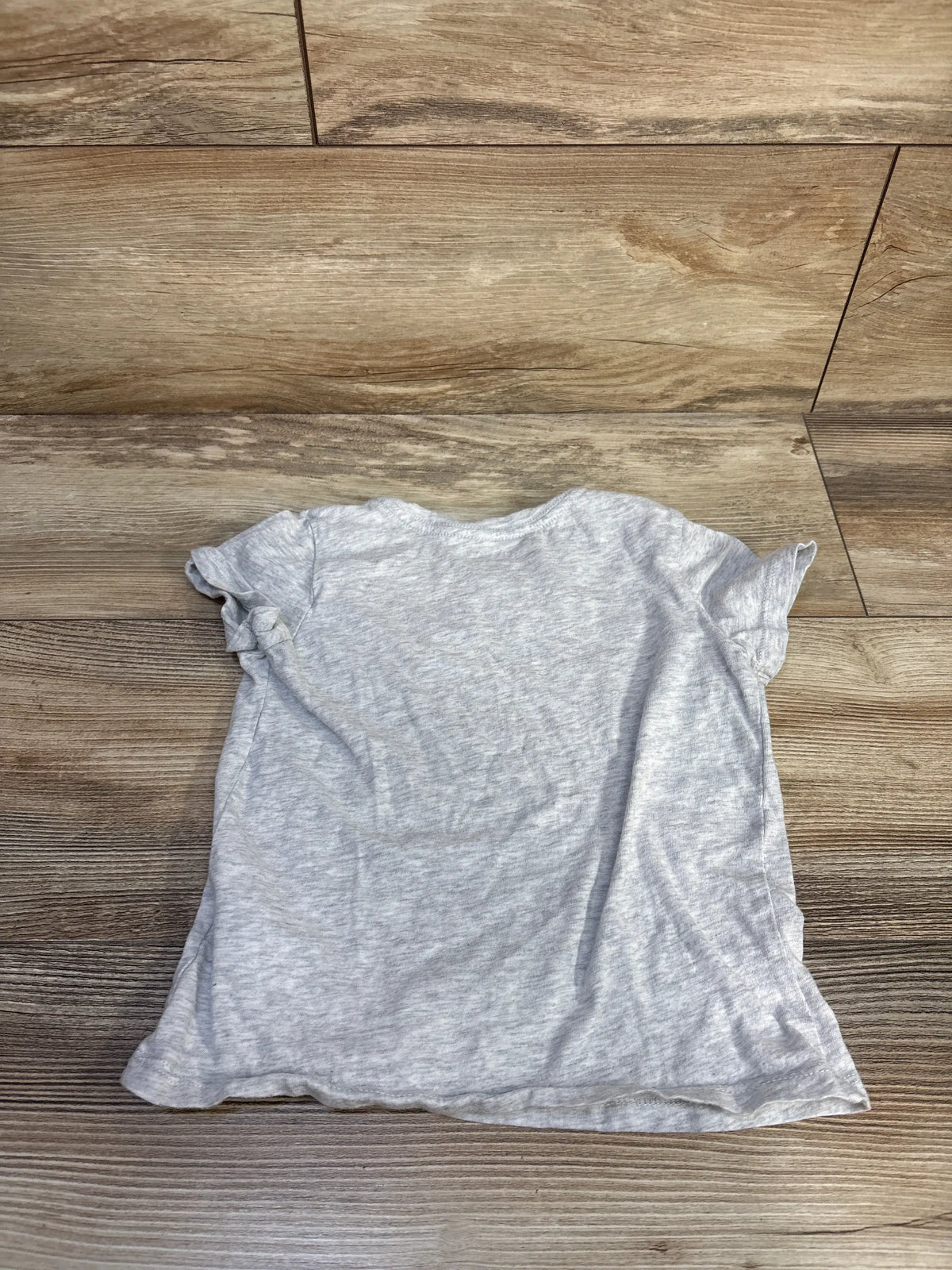 Front view of grey Old Navy children’s shirt in size 5T showcasing short sleeves on wood flooring