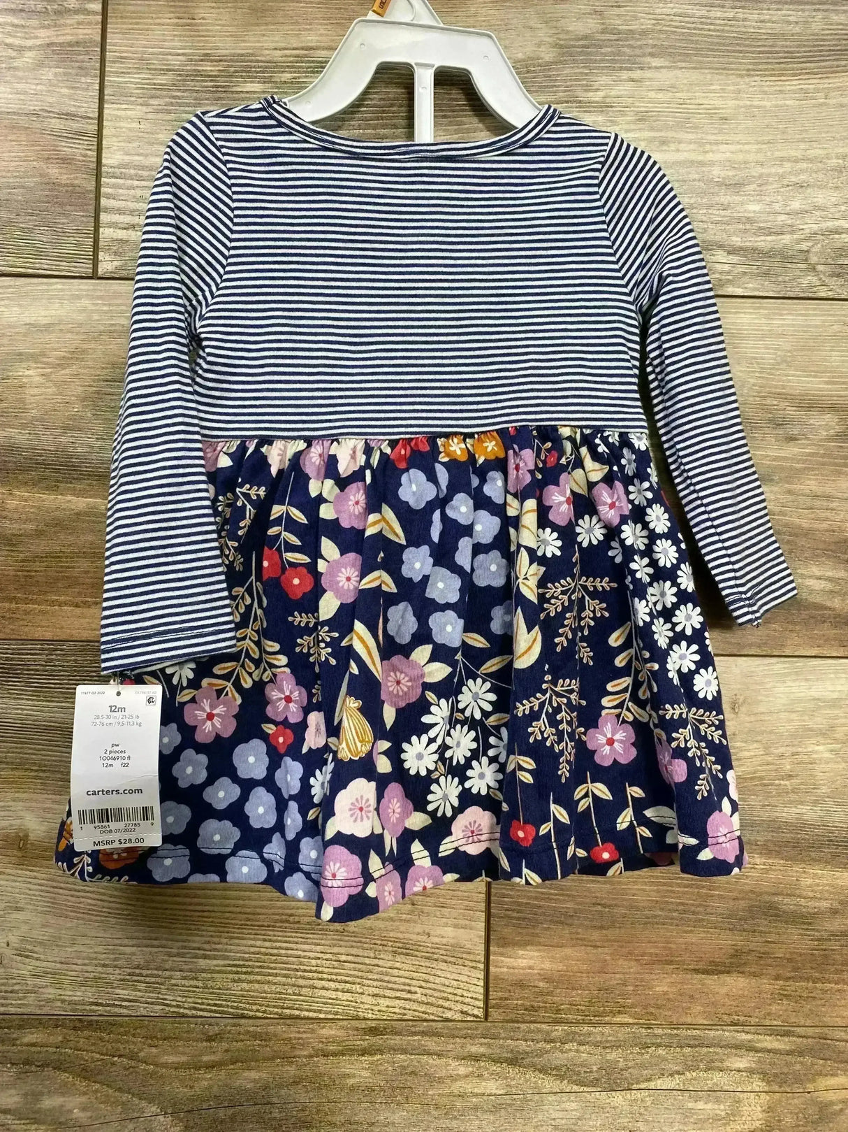 Front view of navy and white striped long-sleeve baby dress with gathered navy floral skirt on wooden background, size 12M