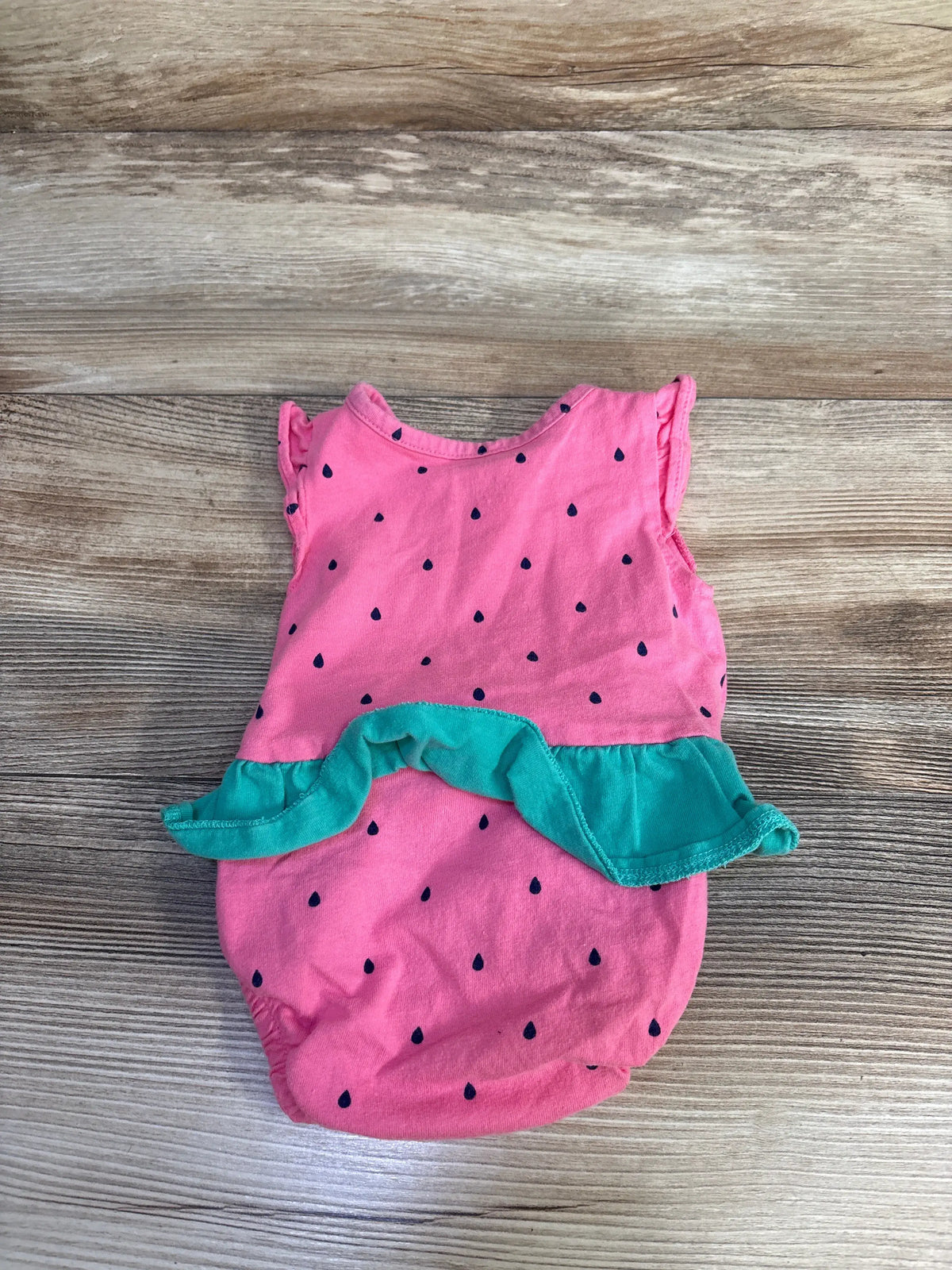 Front view of Carter’s pink watermelon bubble romper showcasing teal ruffle trim and seed print on wood background