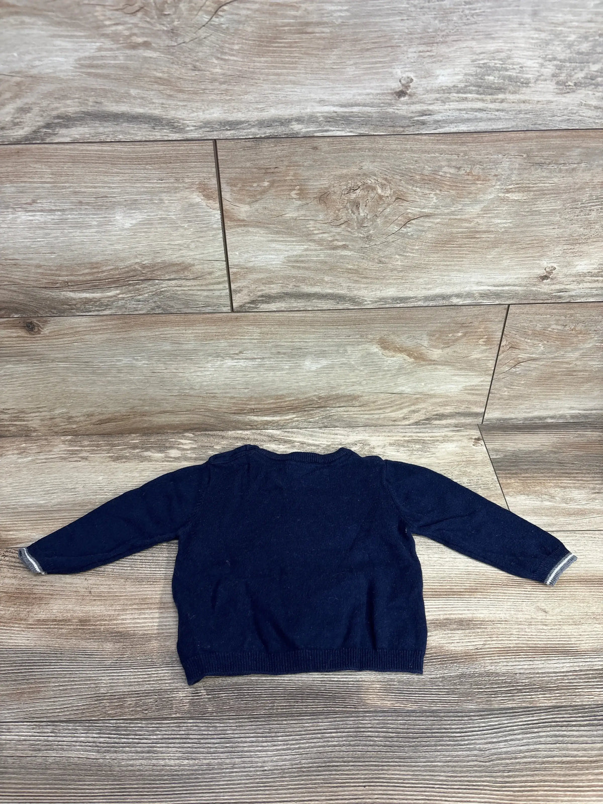 Navy blue long sleeve toddler sweater on wood background, gently used kids clothing