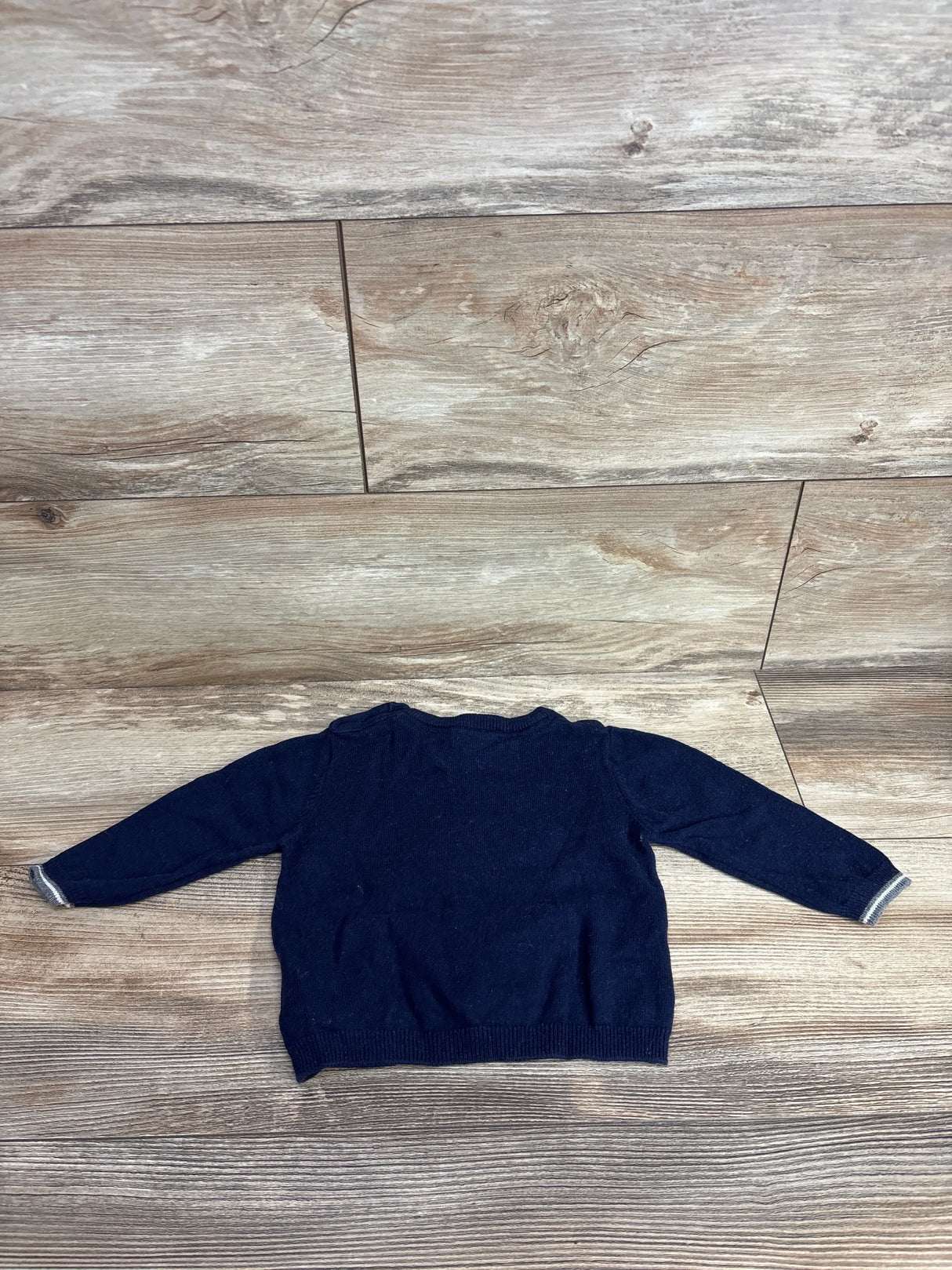 Navy blue long sleeve toddler sweater on wood background, gently used kids clothing
