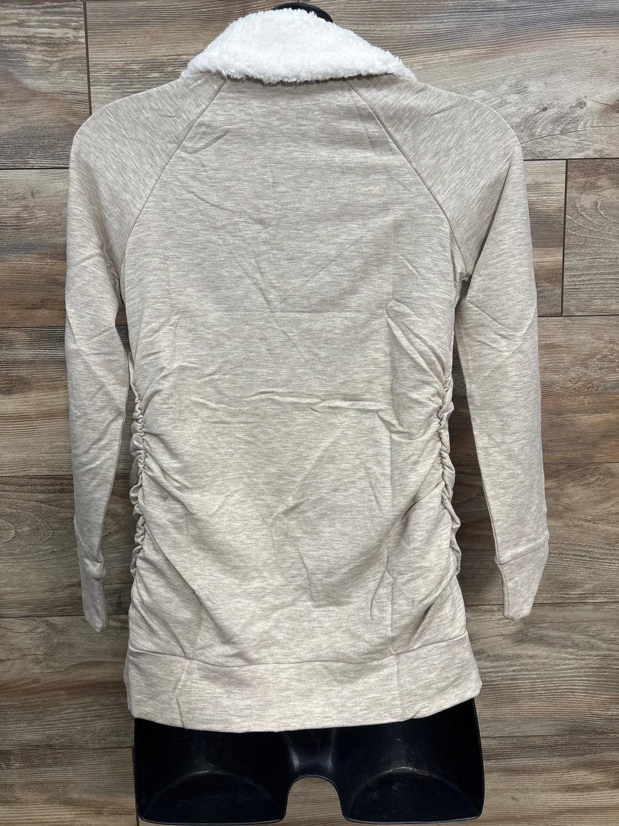 Back view of beige long-sleeve jacket with white sherpa collar on wood floor