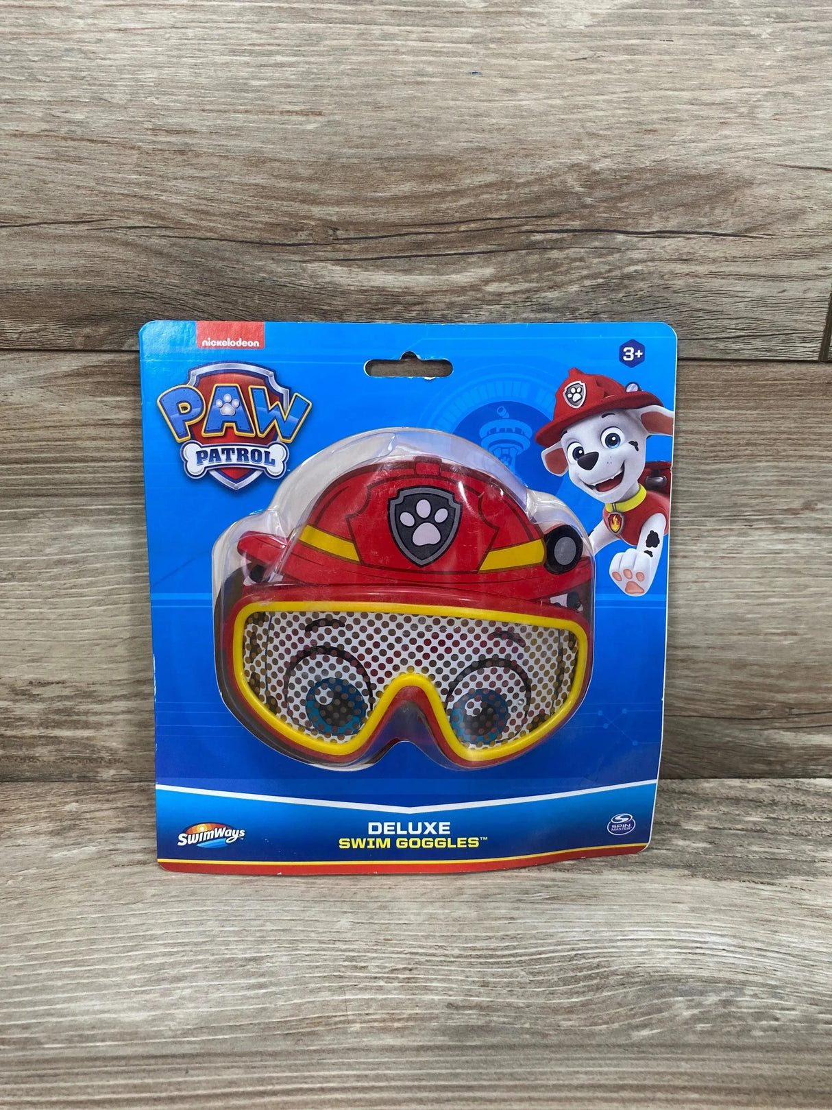 Front view of Paw Patrol Marshall swim goggles with red firefighter helmet and yellow-trimmed lenses in blue retail package