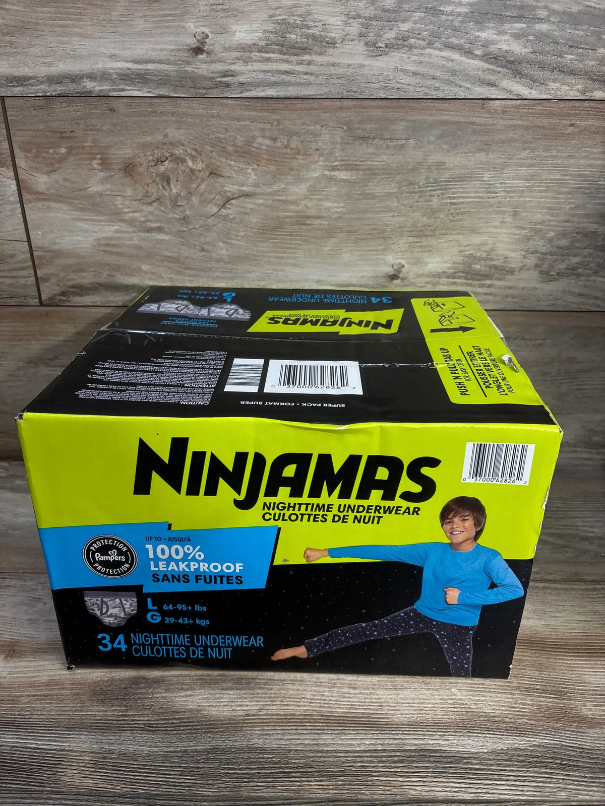Front view of Ninjamas 34-count nighttime underwear box showing Ninjamas logo, 100% leakproof claim and size Large (64–95 lbs) on wood floor background