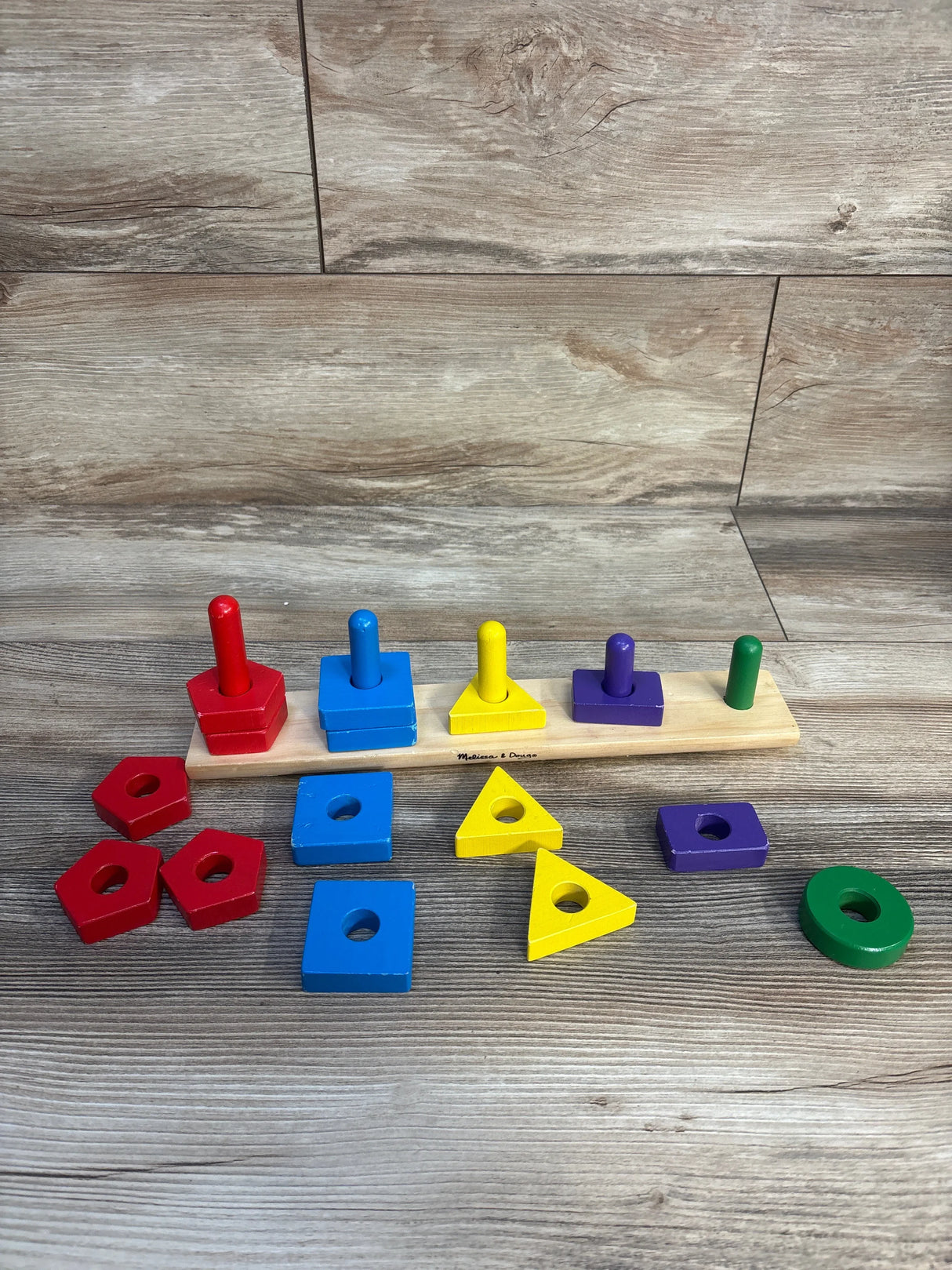 Wooden shape sorting toy with colorful geometric blocks for kids on wood floor