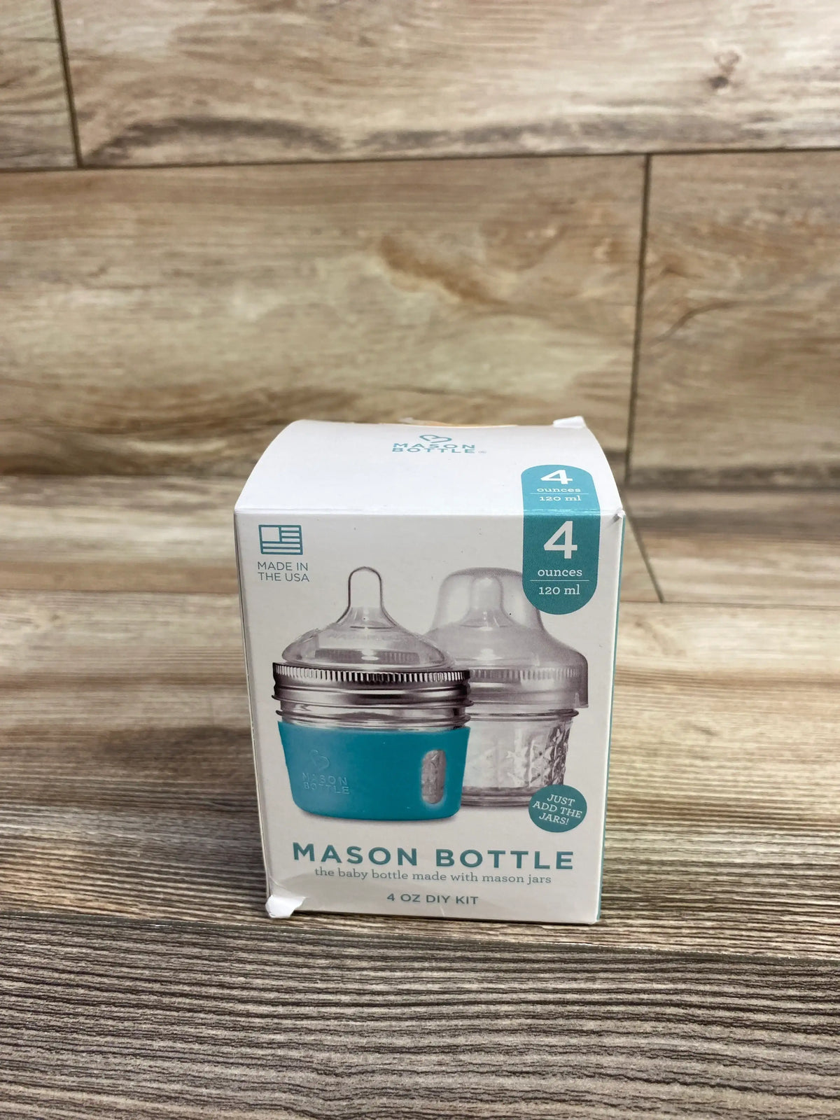 Front of Mason Bottle 4 oz DIY kit box showing two bottle nipples and teal silicone sleeve on wood background