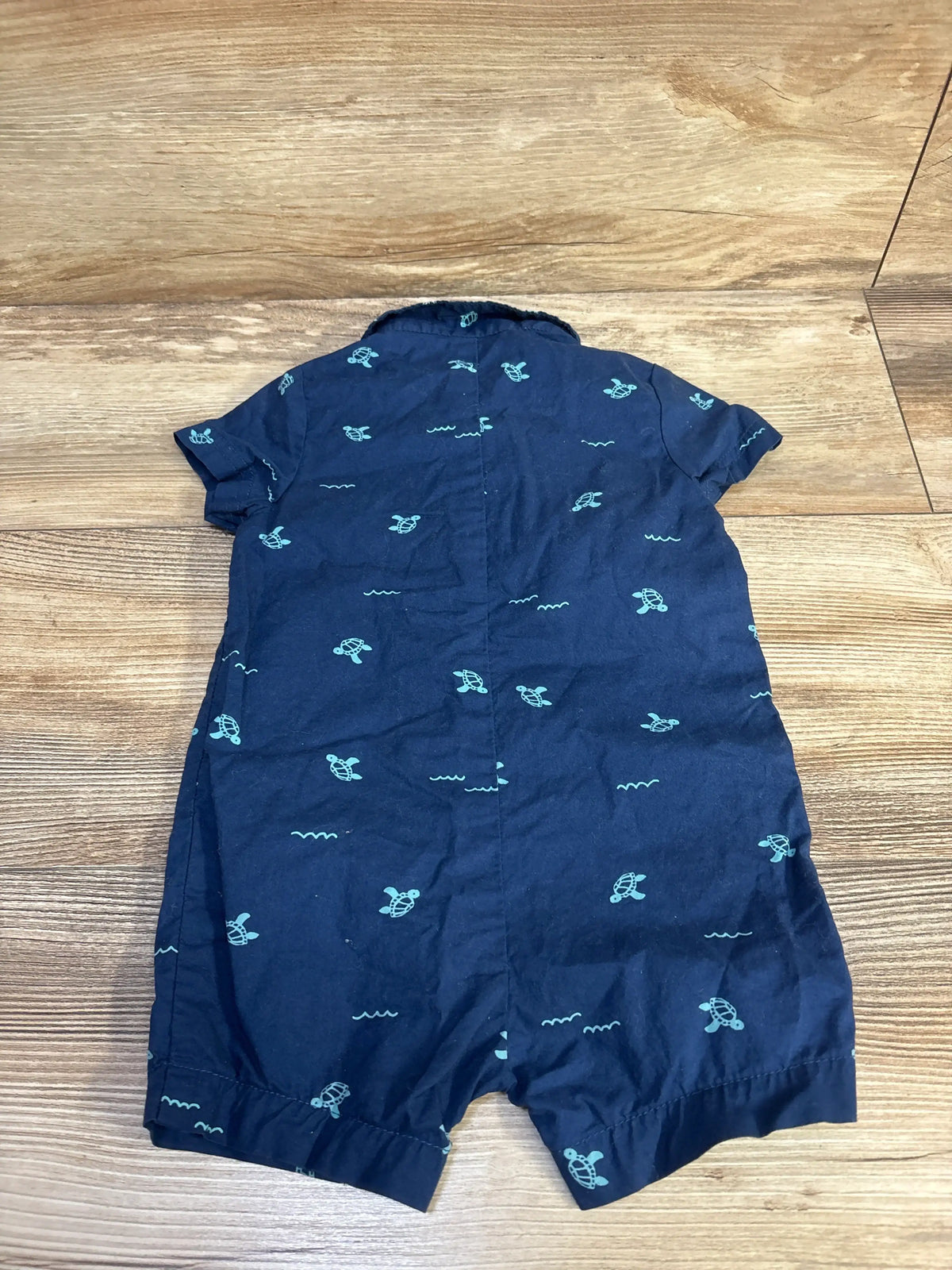 Flat lay of Child Of Mine navy turtle polo romper showcasing short sleeves, polo collar, and turtle pattern