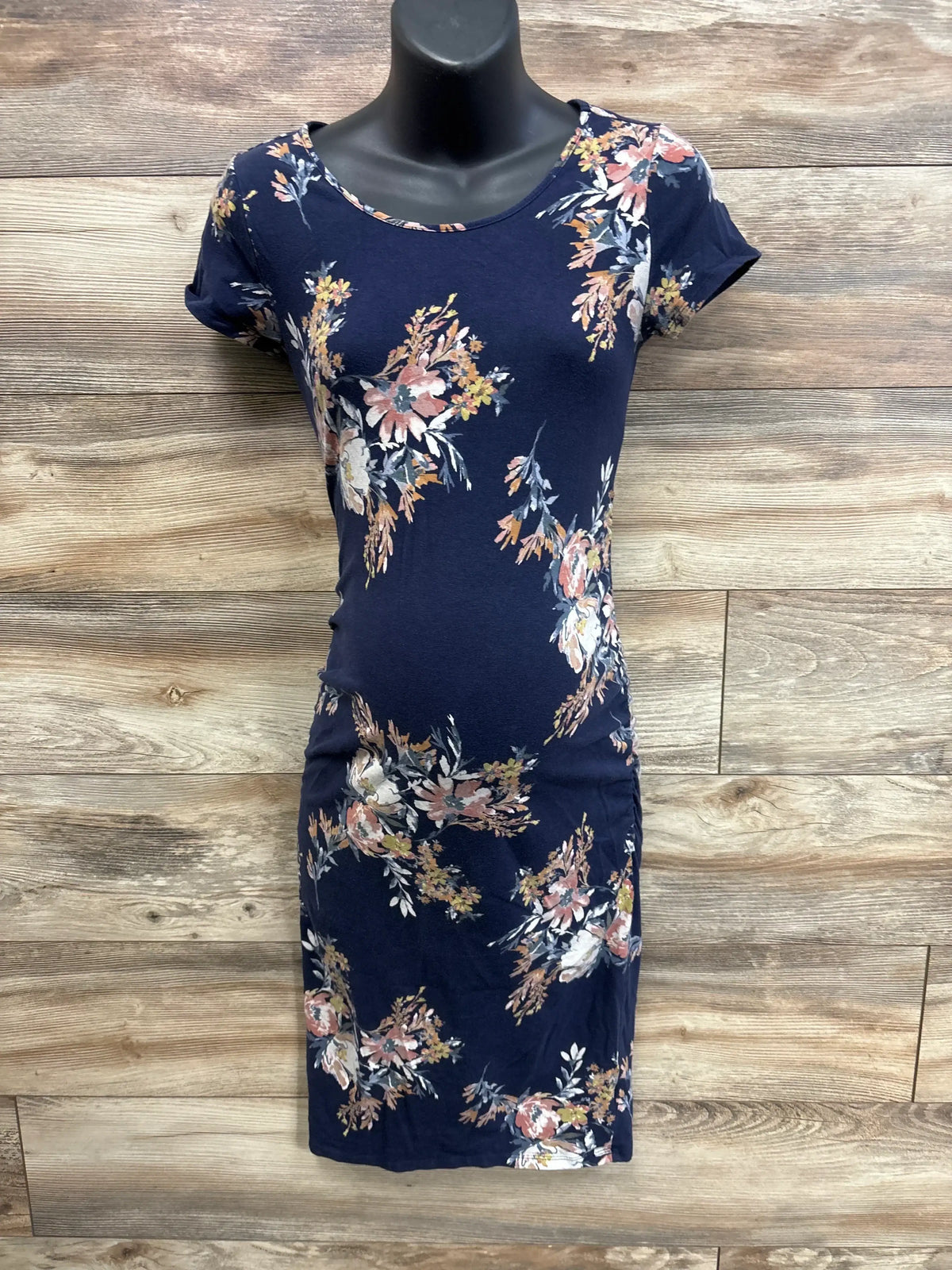 Front view of navy maternity bodycon dress with floral print, short sleeves, knee-length on mannequin against wood background