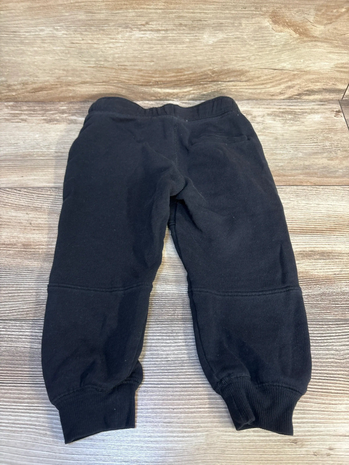 Black toddler jogger pants with elastic waistband on wooden background