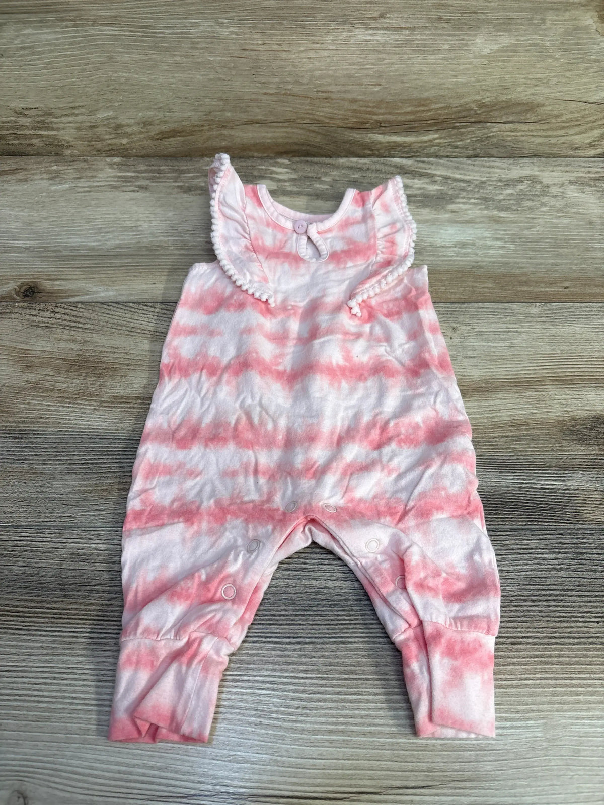 Front view of newborn pink tie dye romper showcasing ruffled collar and snap closures with wood plank background