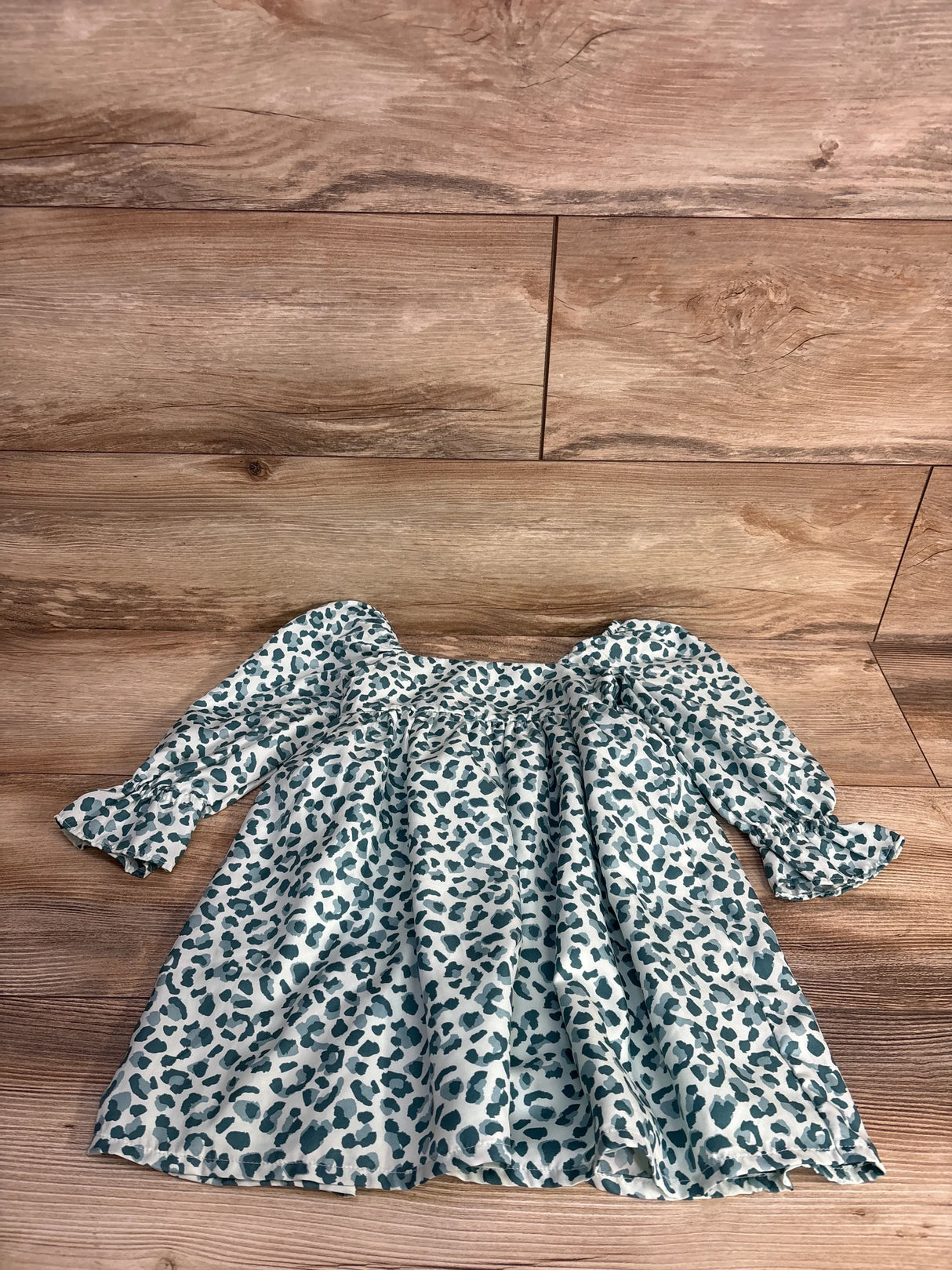 Long sleeve baby dress with blue and gray leopard print on wooden floor