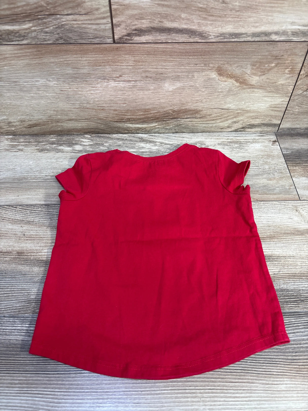 Back view of red Minnie and Daisy toddler shirt size 5T showing ruffled sleeves and curved hem on wood background