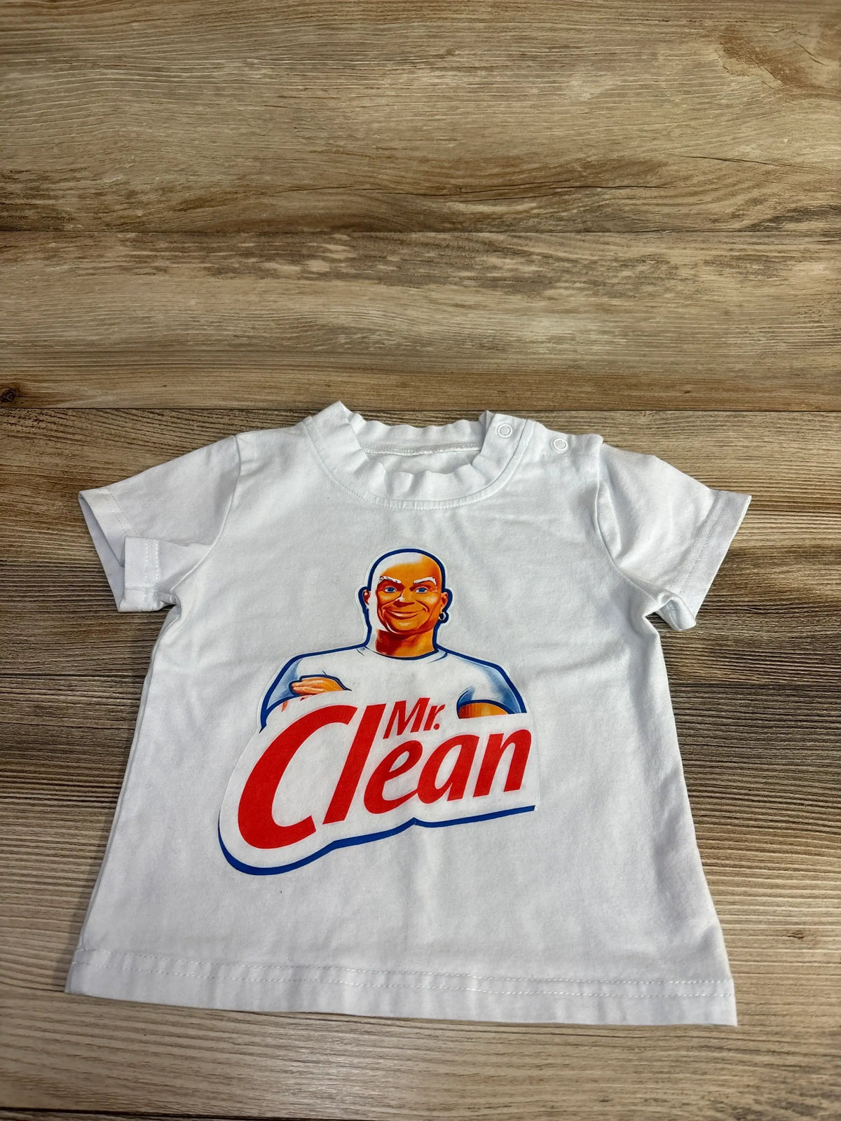 White toddler t-shirt with Mr. Clean logo and character on wood background