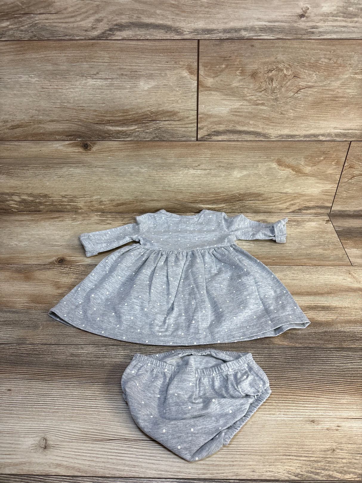 Gray polka dot baby dress and bloomers set on wooden floor