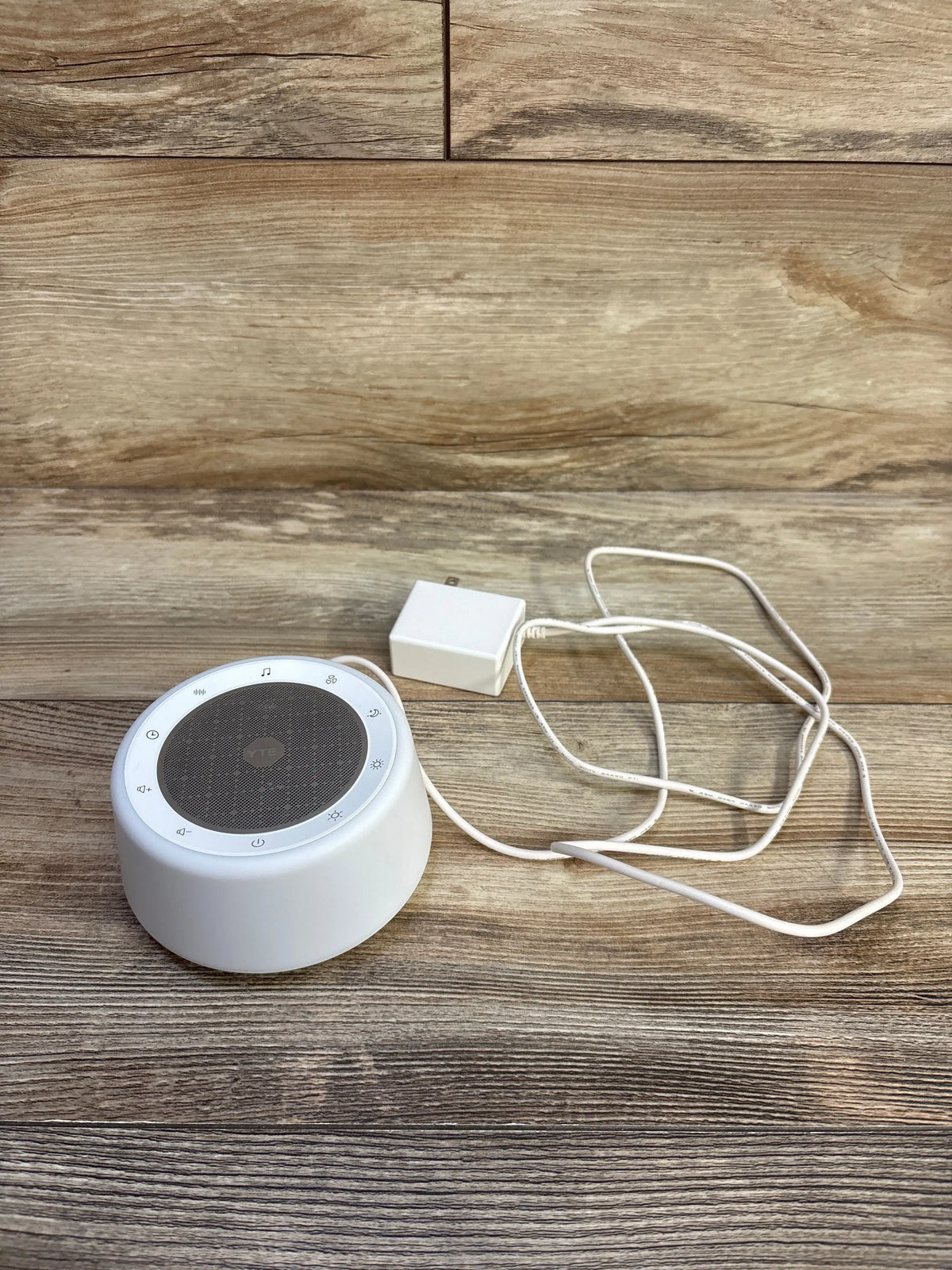 White YTE TP1 White Noise Sound Machine with power adapter on a wooden surface.