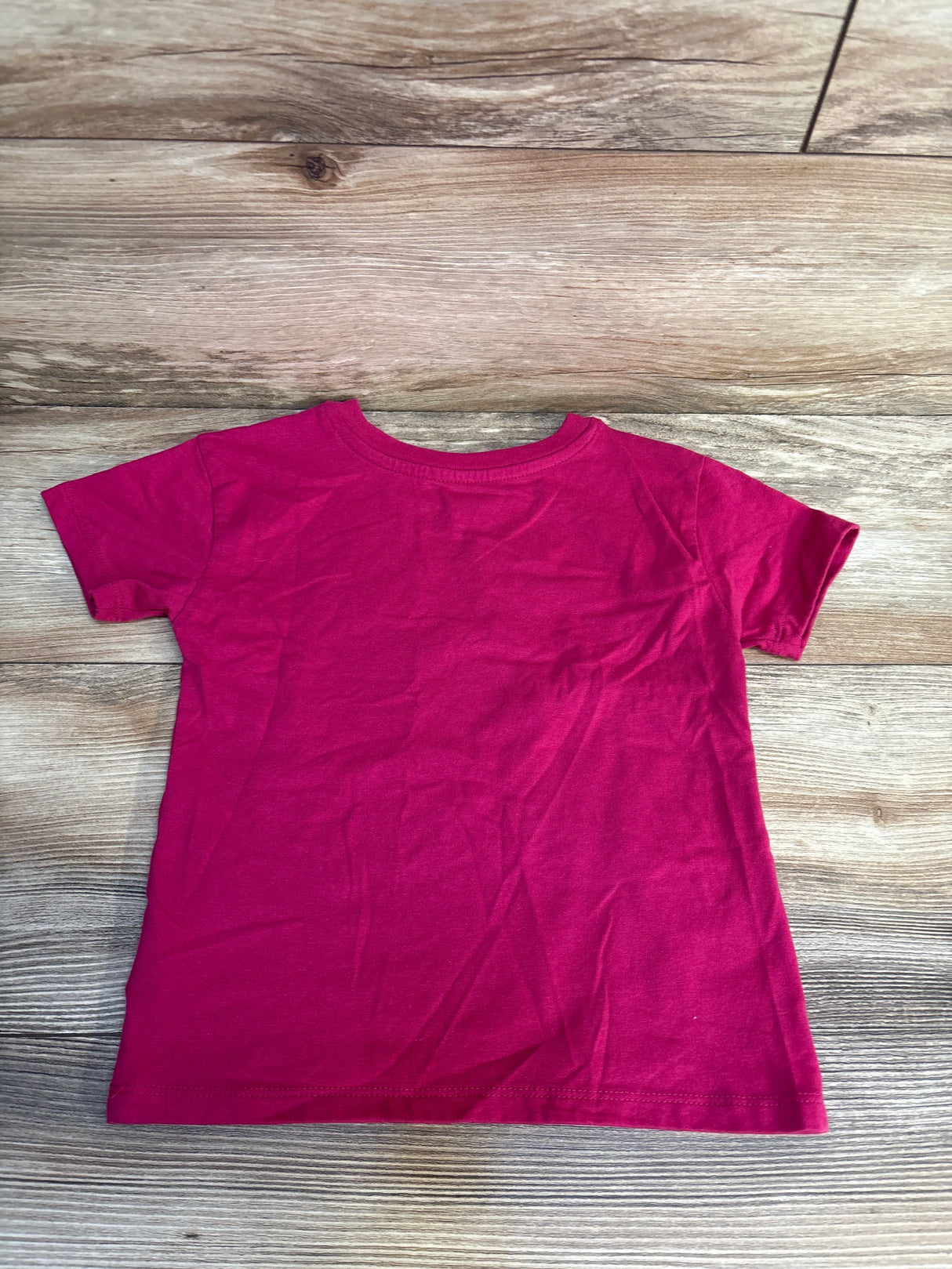 Bright pink kids short sleeve t-shirt on wood floor, perfect for casual wear or resale