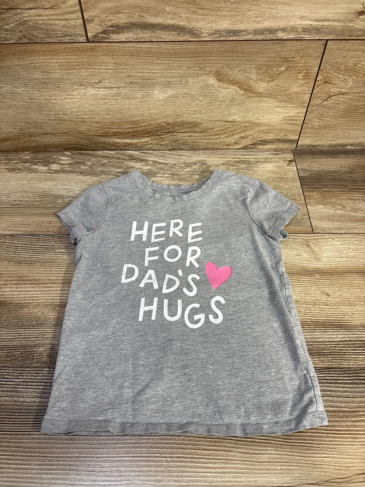 Front view of a grey Cat and Jack toddler shirt showcasing the Here for Dads Hugs graphic with a wood floor background