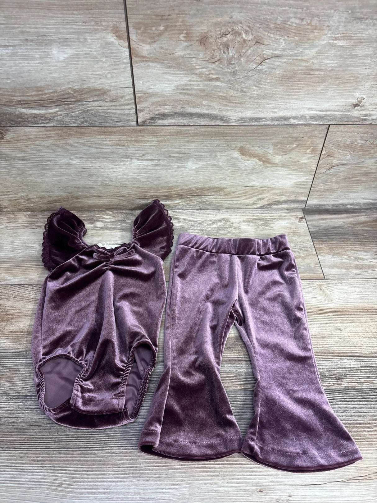 Purple velvet toddler outfit with ruffle sleeve top and flared pants on wood background
