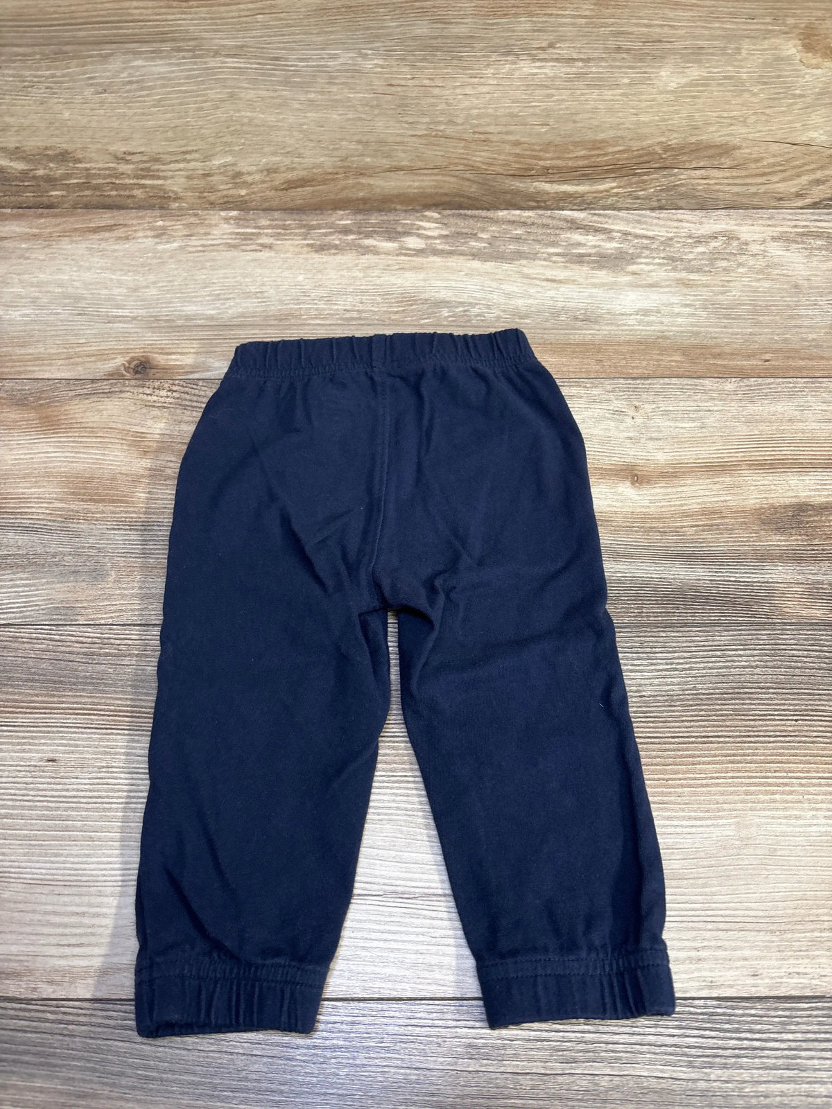 Front view of Baby Gap navy toddler joggers showing elastic drawstring waistband and gathered cuffs on wood background