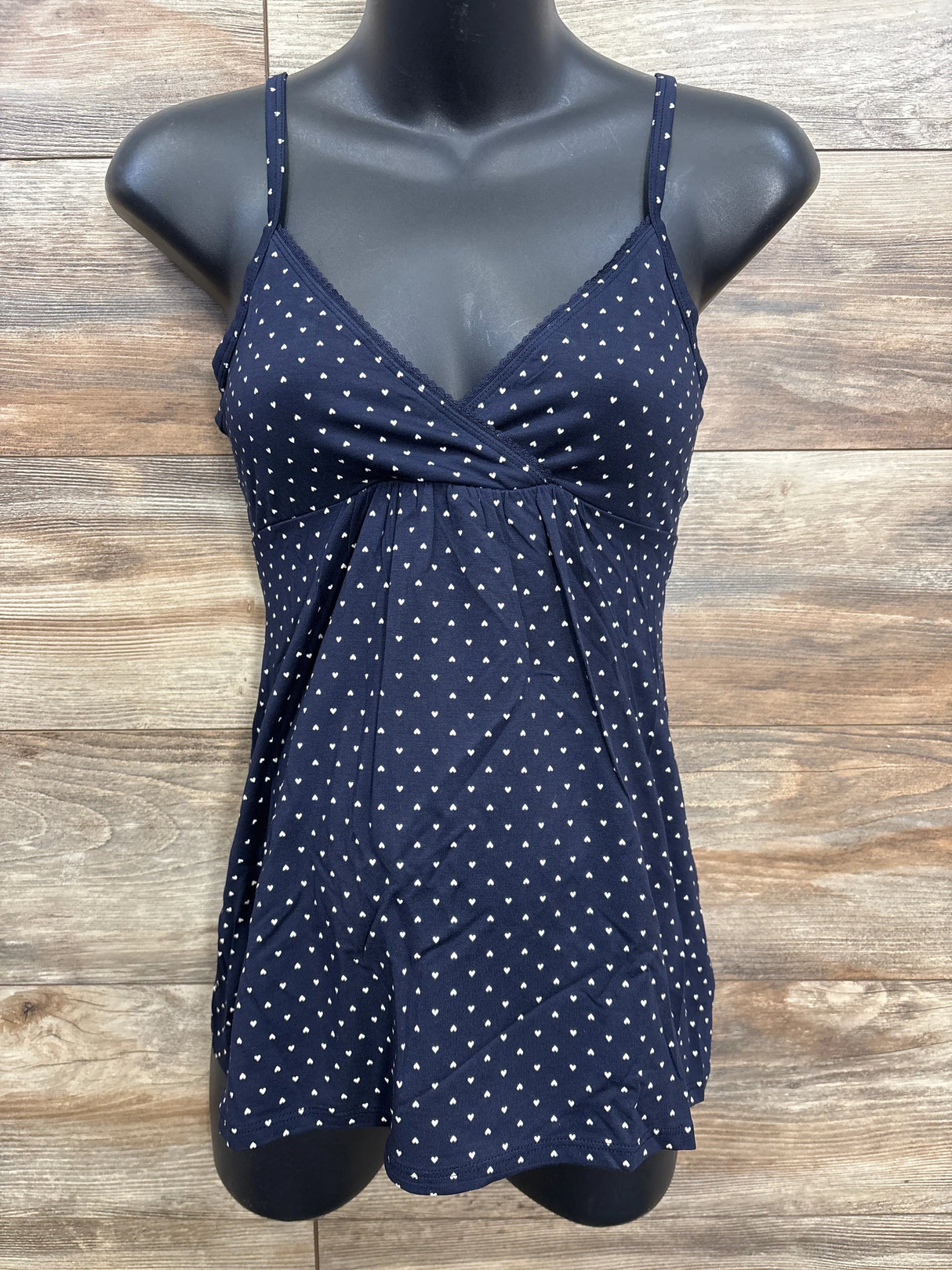 Navy blue maternity tank top with white heart pattern on black mannequin against wood wall