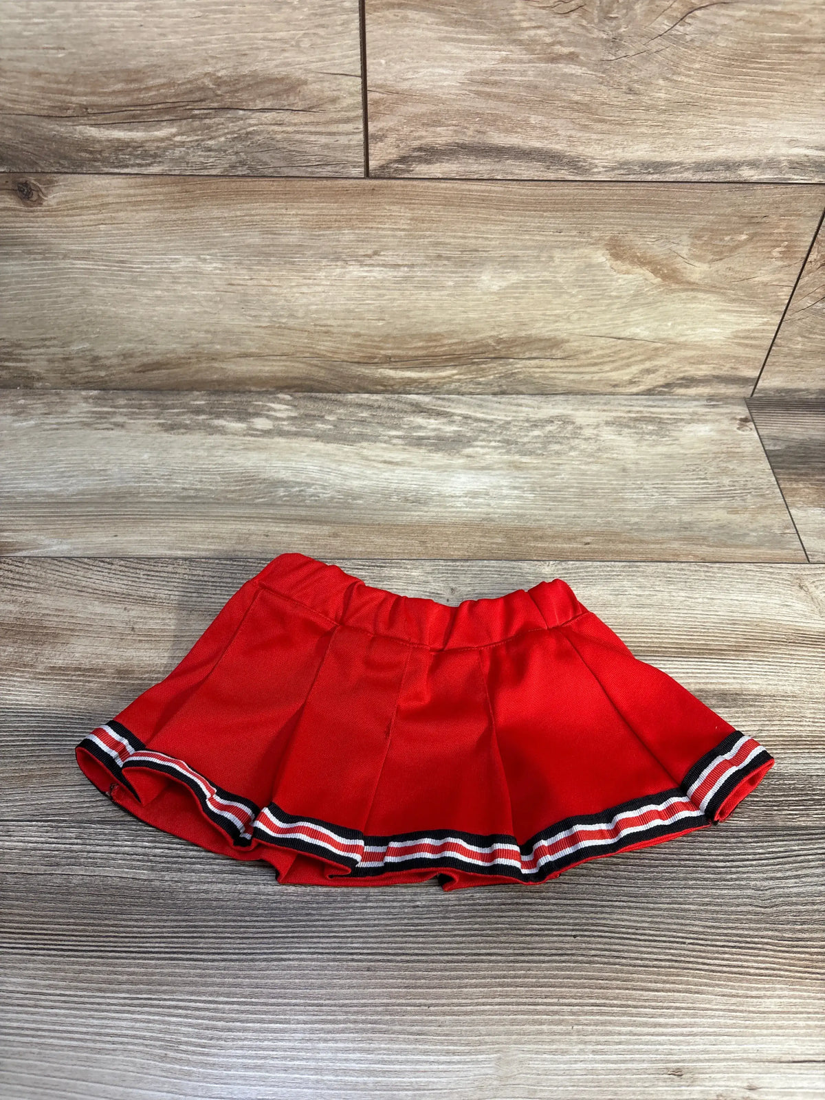 Front view of NCAA UNLV red skirt in size 12 months showcasing elastic waistband and striped hem on a wood-look floor