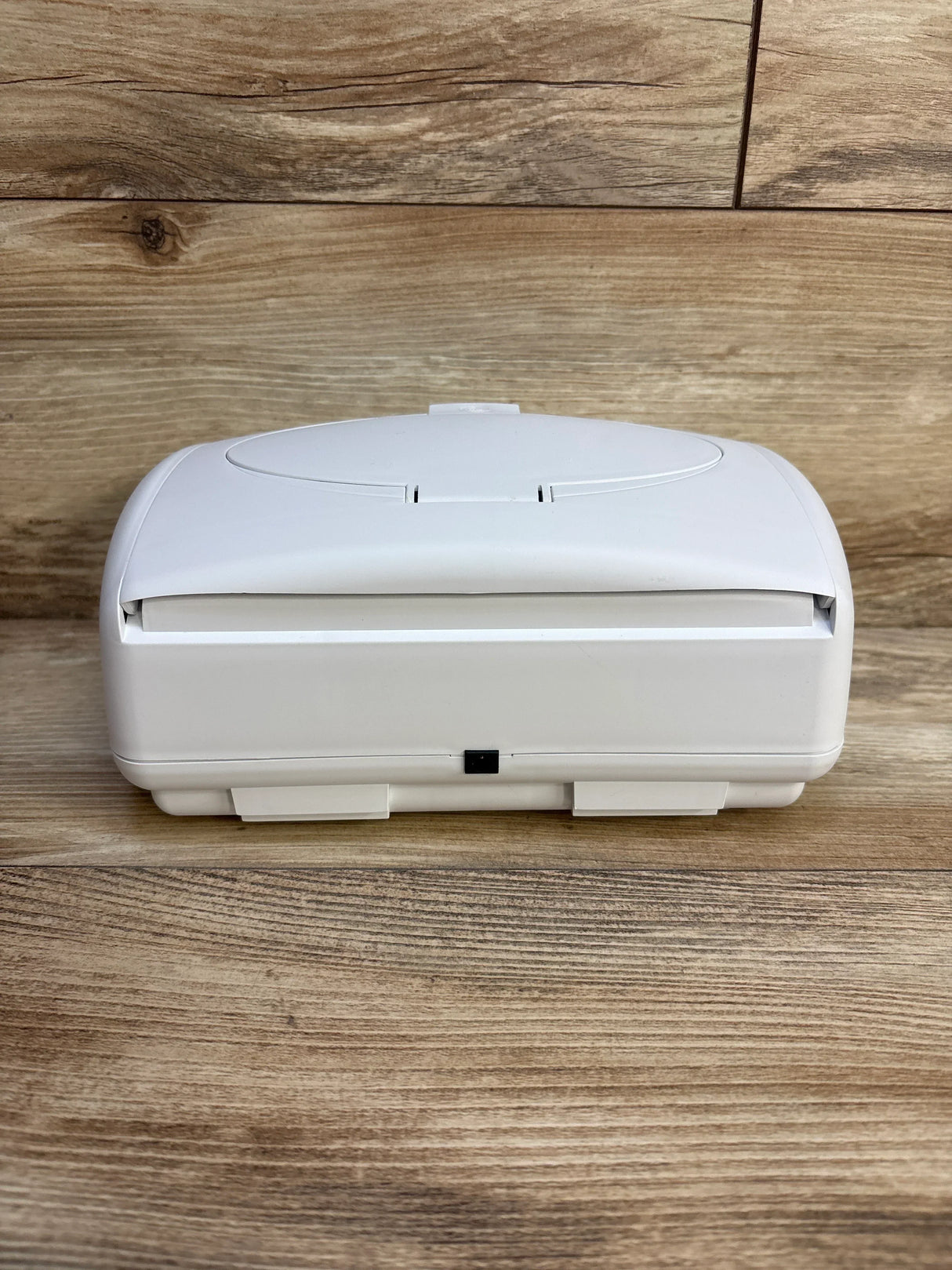 Front view of Prince Lionheart Ultimate Wipes Warmer showing closed lid, front power port, and latch on a wood plank background