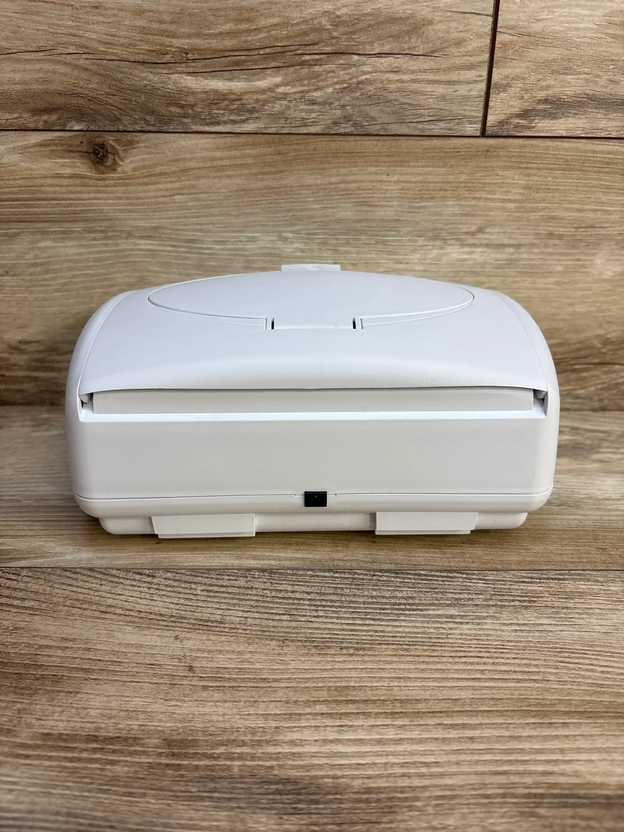 Front view of Prince Lionheart Ultimate Wipes Warmer showing closed lid, front power port, and latch on a wood plank background