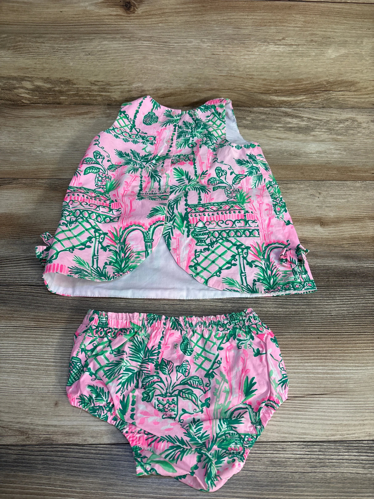 Pink and green tropical print baby dress with matching bloomers on wood background