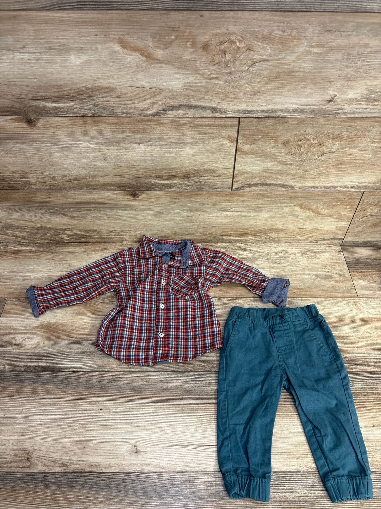 Plaid long-sleeve shirt and teal pants toddler outfit on wood floor